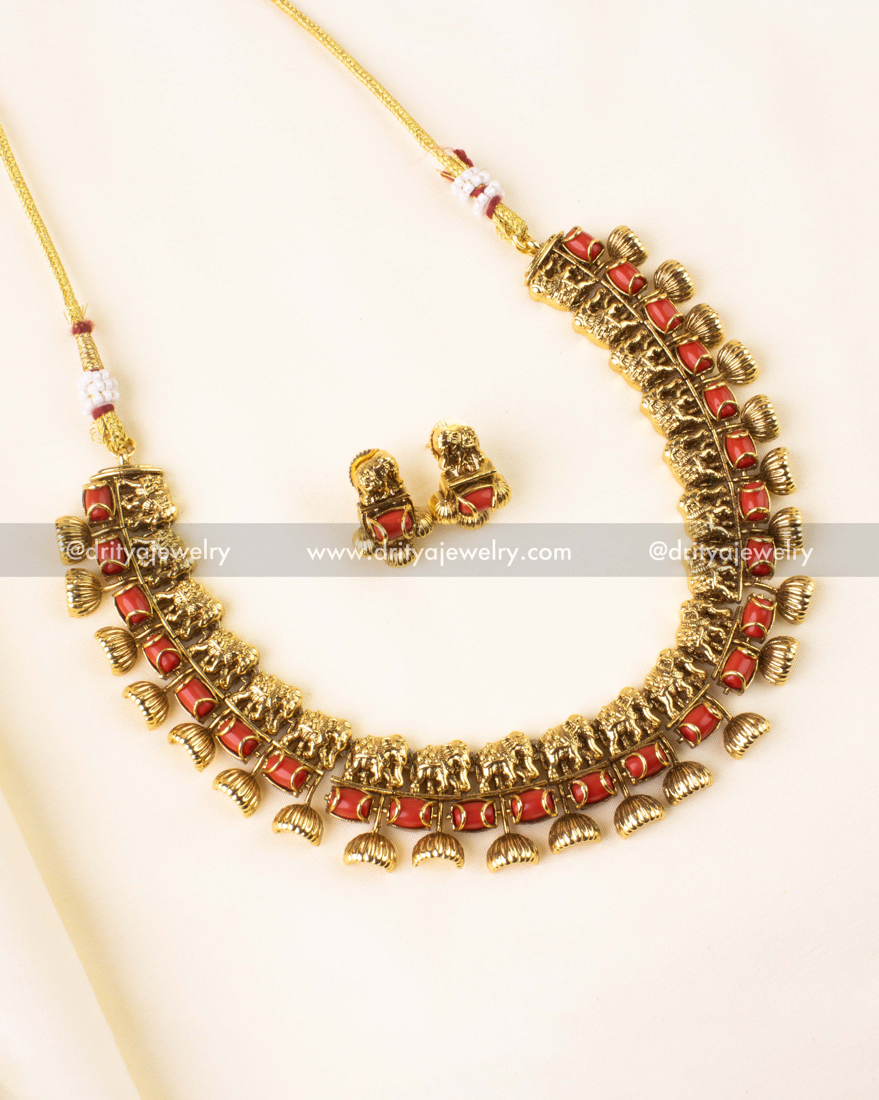 Short antique gold necklace set with coral beads and elephant motifs, paired with matching earrings.