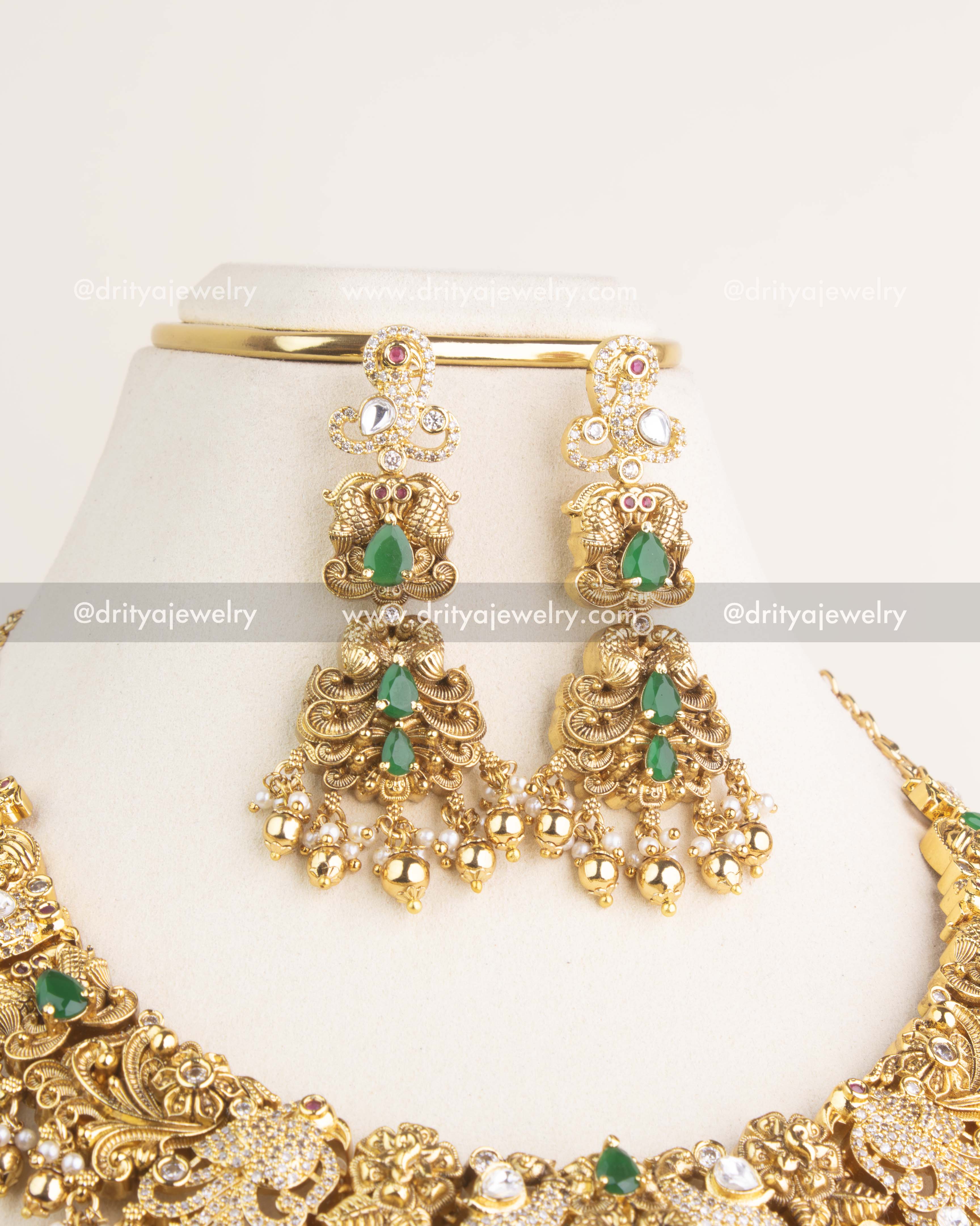 Pair of antique danglers designed with intricate polki kundan work, green teardrop stones, pearls, and golden bead hangings.