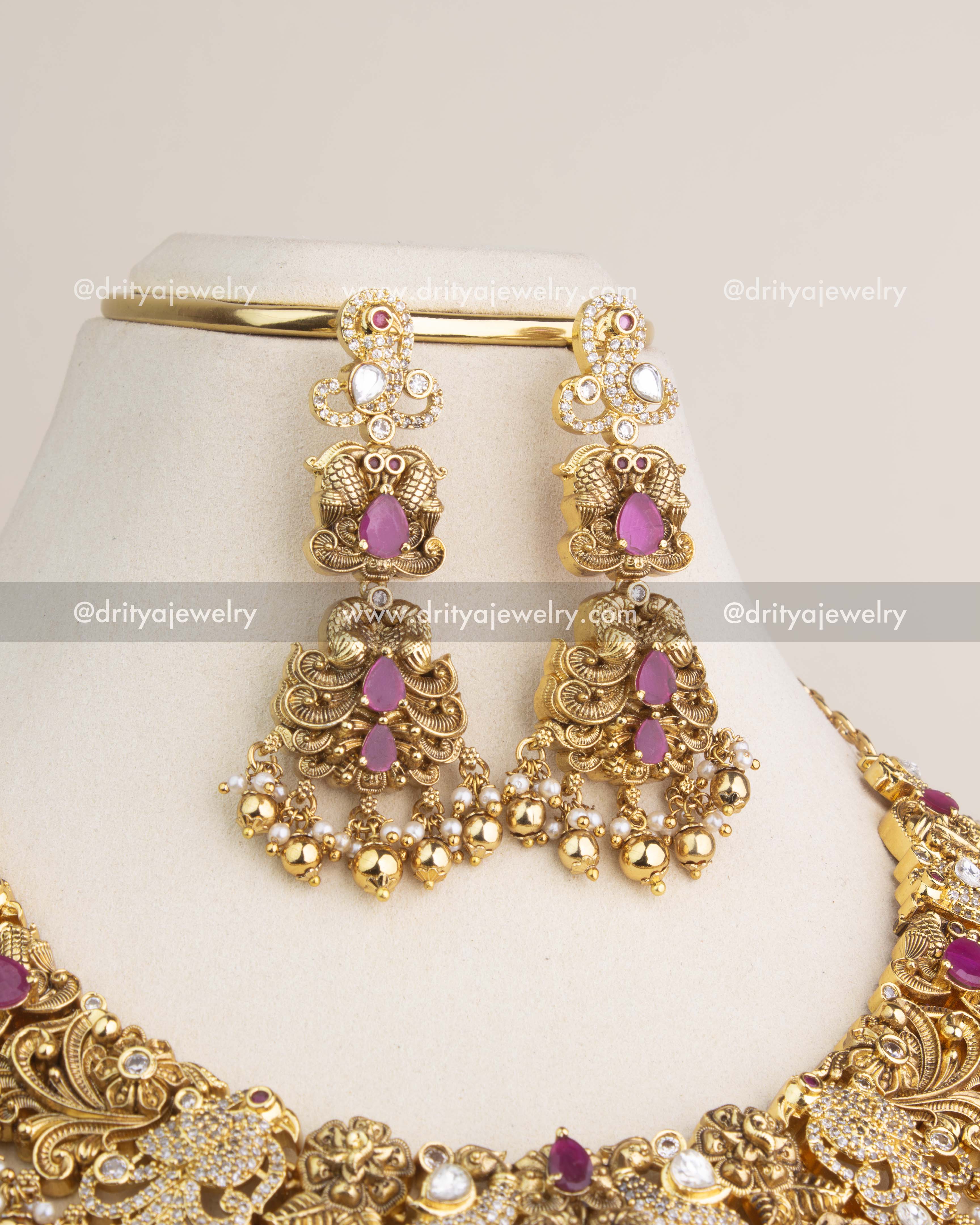 Pair of antique earrings featuring ruby-red stones, polki kundan detailing, pearls, and dangling gold beads.