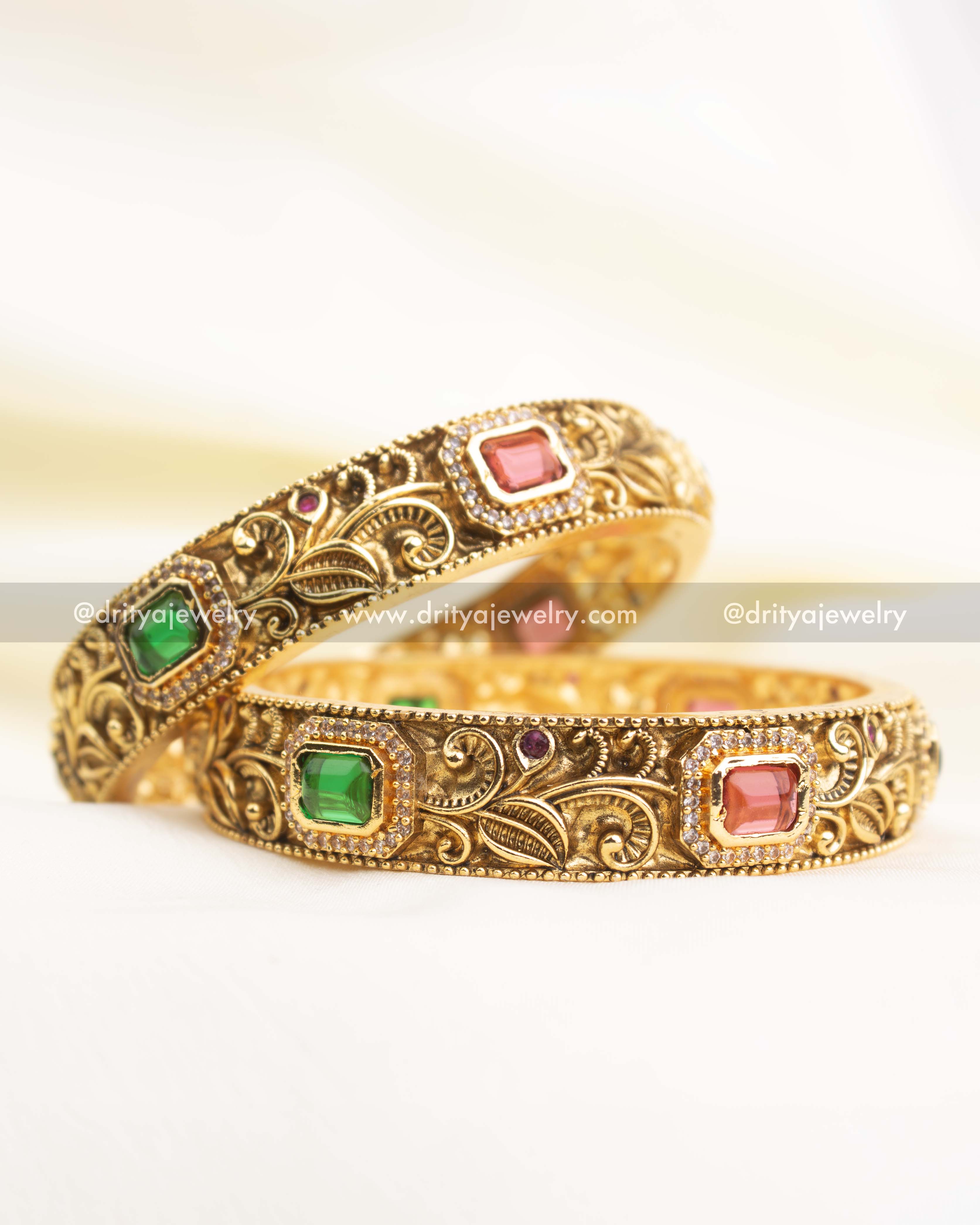Premium antique gold bangles with floral nakshi engraving and rectangular ruby-pink and green stones.