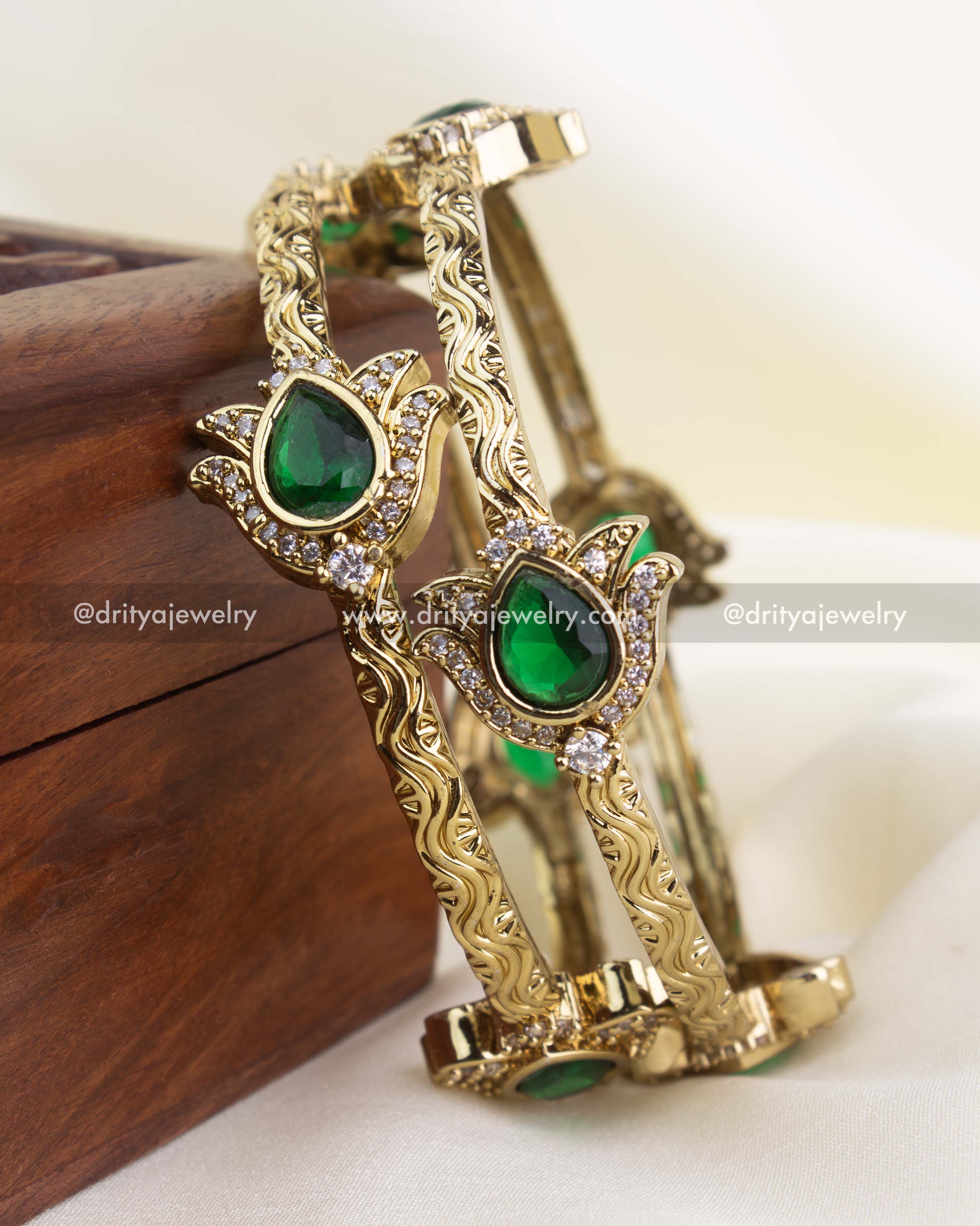 Premium antique gold kada set with emerald green teardrop stones and CZ accents.