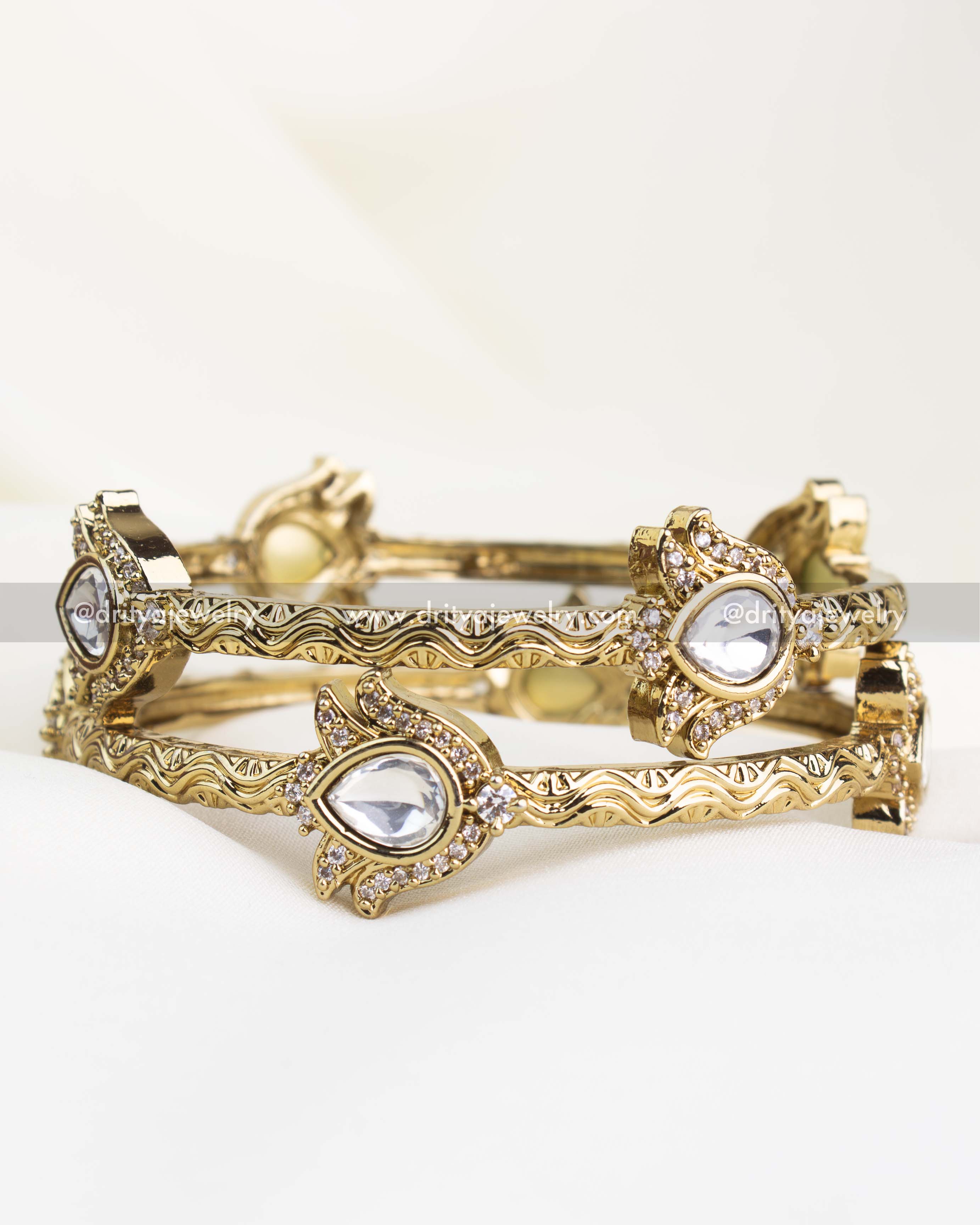 Antique gold kada set with polki-style white stones and filigree-carved edges.