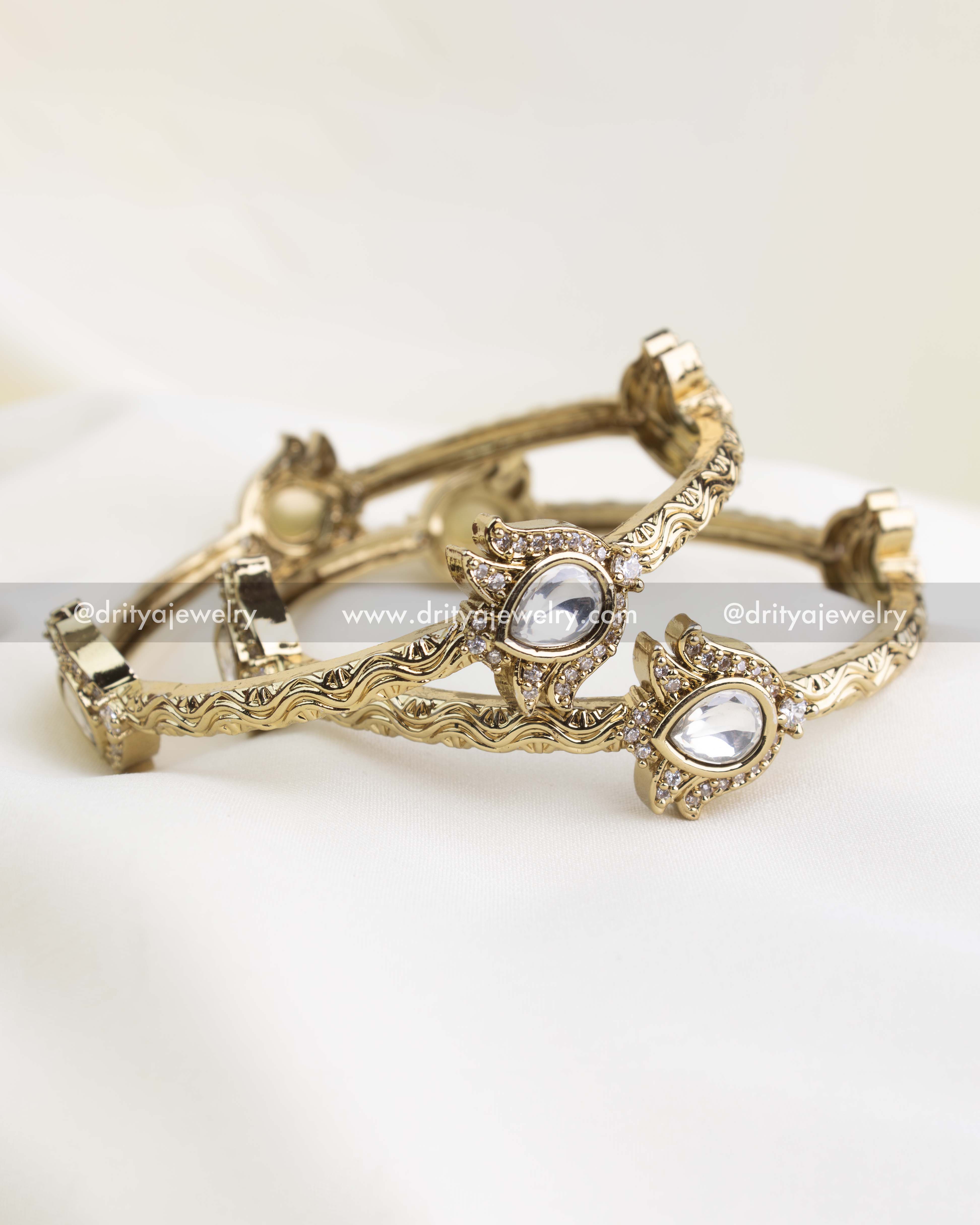 Antique gold kada set with polki-style white stones and filigree-carved edges.