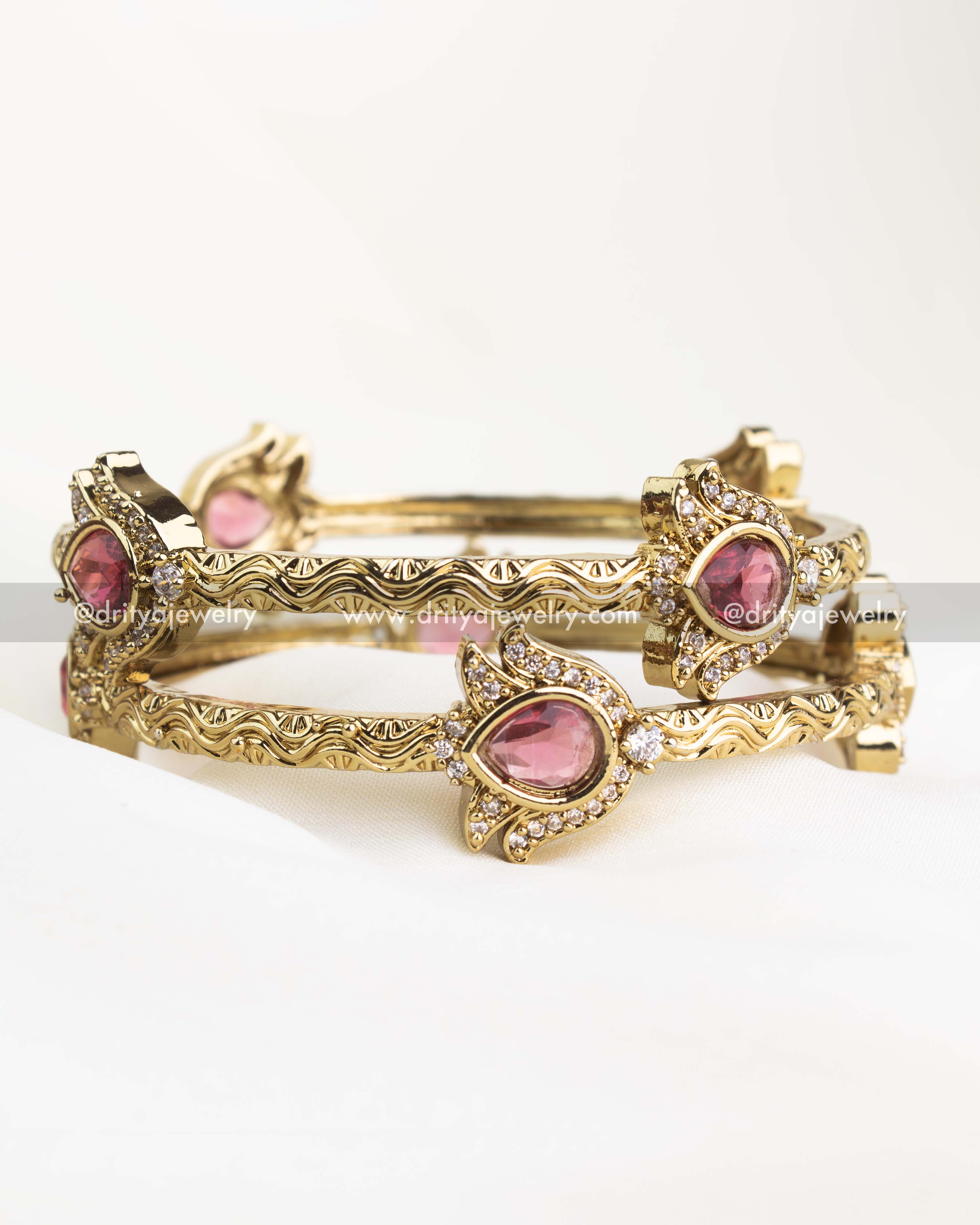Antique gold kada pair with ruby red centerpiece and CZ-studded floral setting.