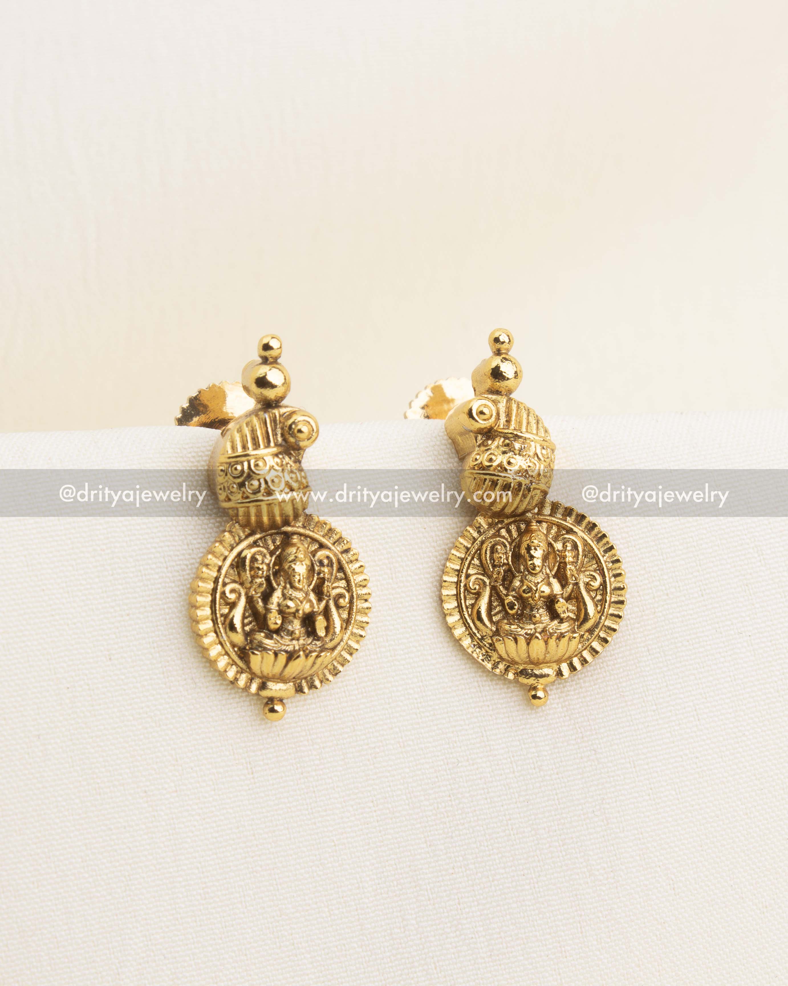 Matching antique gold Lakshmi stud earrings with dome detailing and temple-inspired finish.