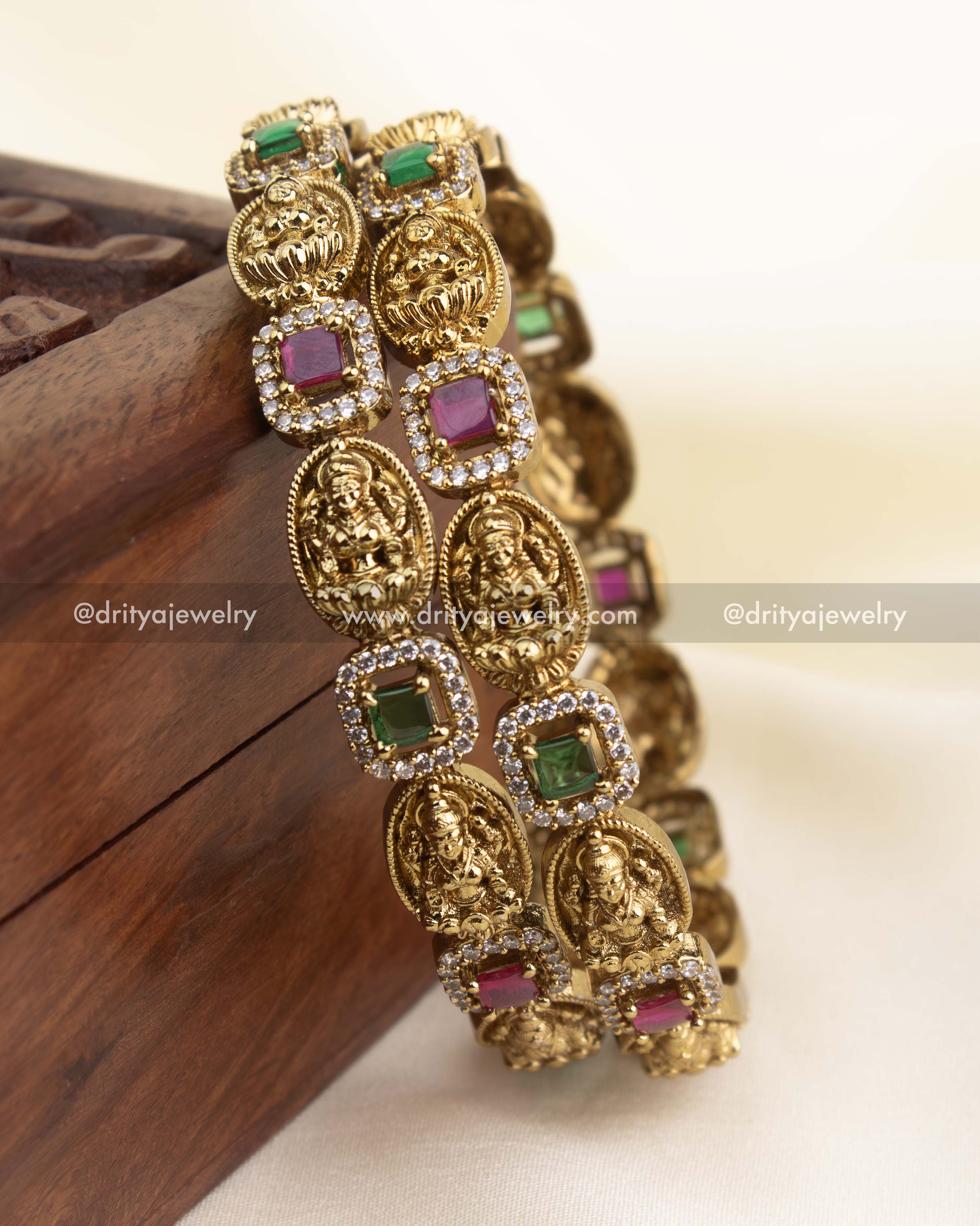 Set of antique gold temple bangles with Lakshmi panels and alternating green and ruby square stones with CZ halos.