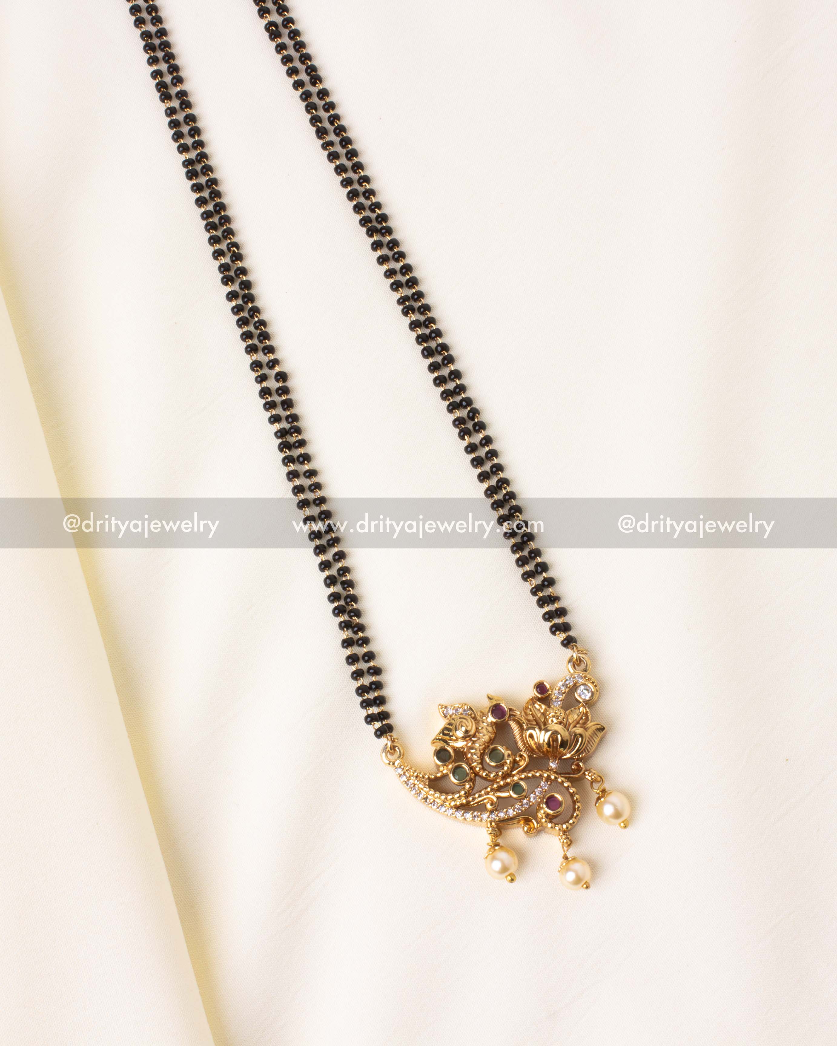 Detailed close-up of the gold-plated peacock pendant with sparkling stones and pearl embellishments on a black beads mangalsutra.