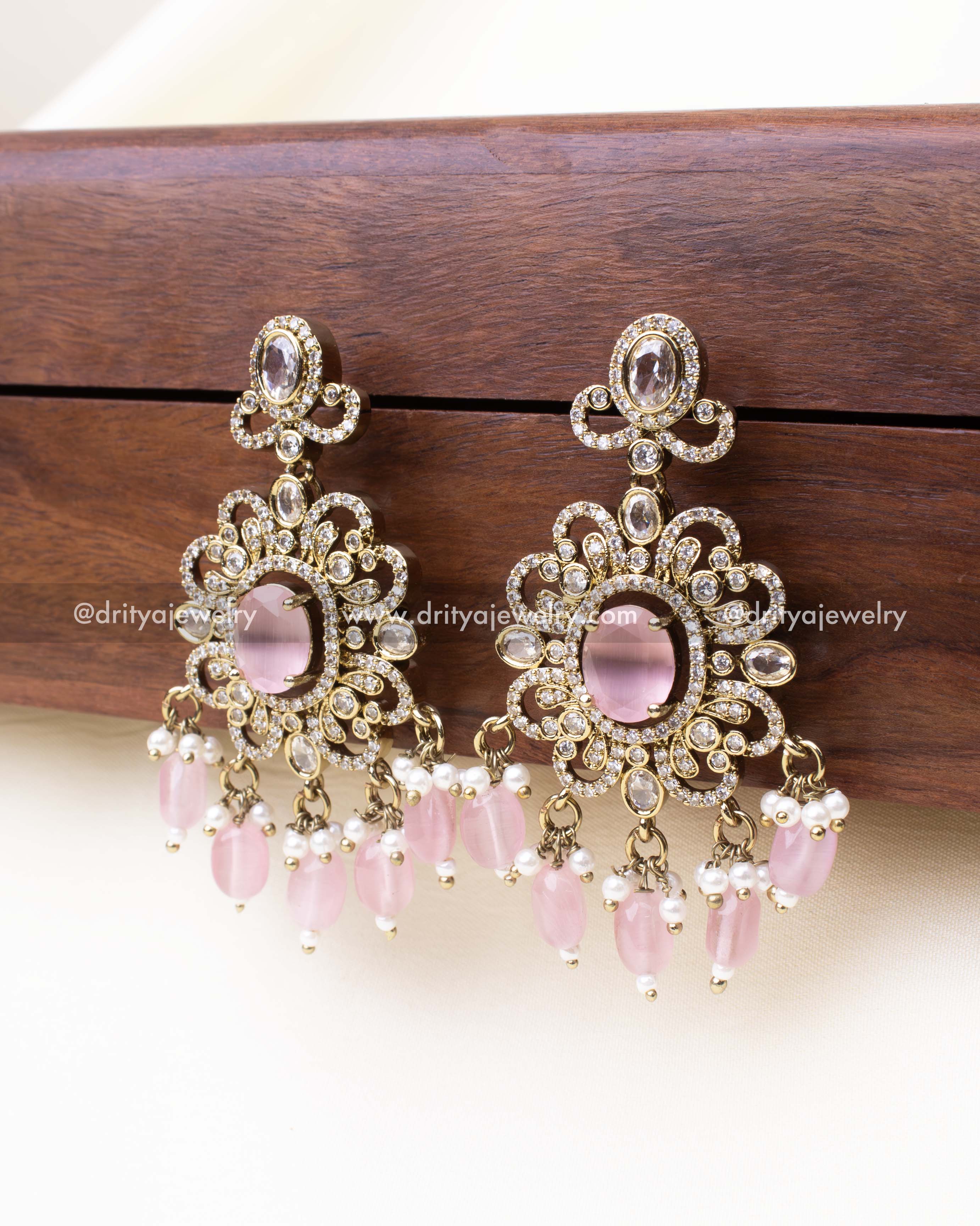 Ornate blush pink drop earrings with floral stone design and hanging beads.
