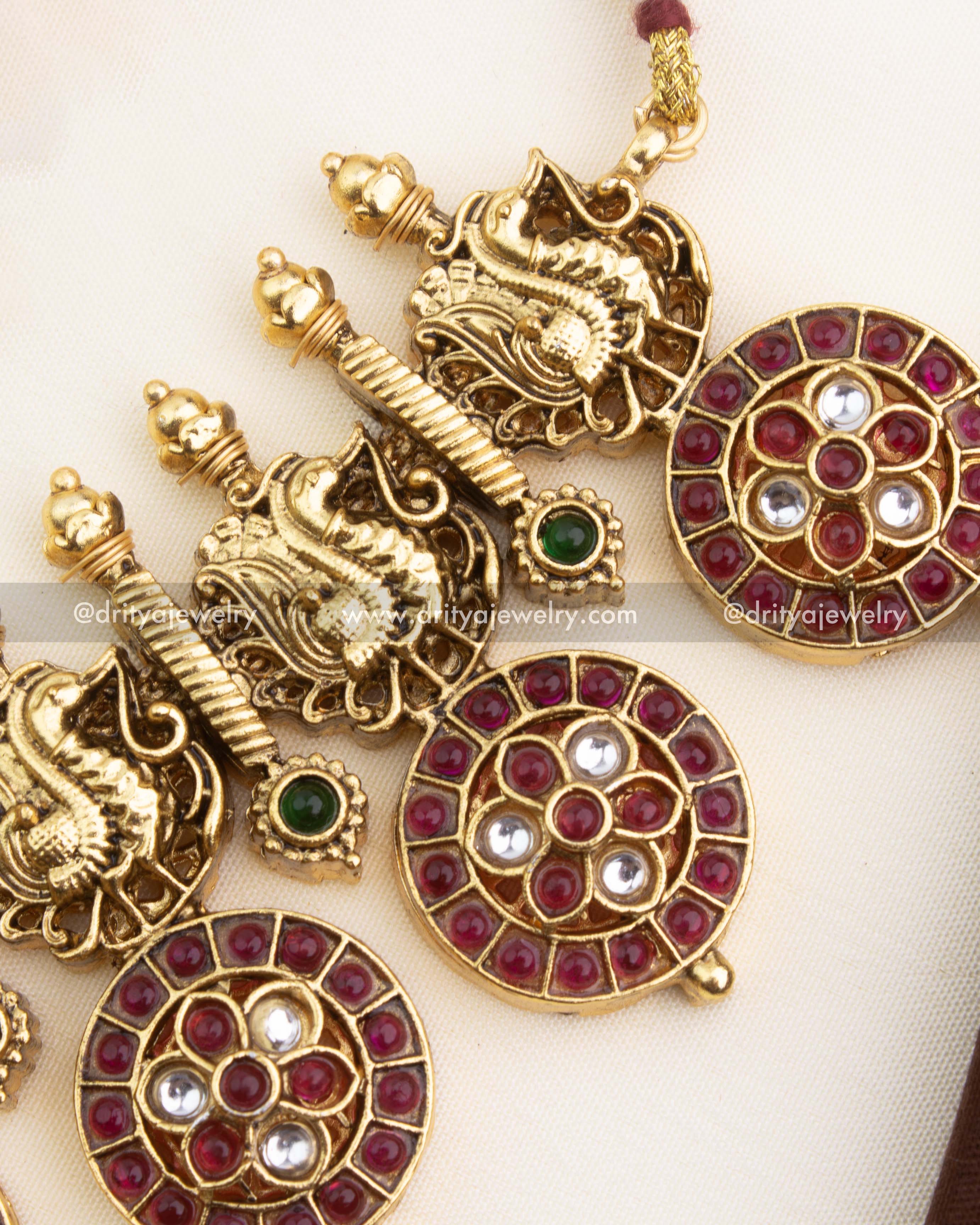 Close-up of ruby bottu discs, white CZ stones, green accents, and antique gold detailing.