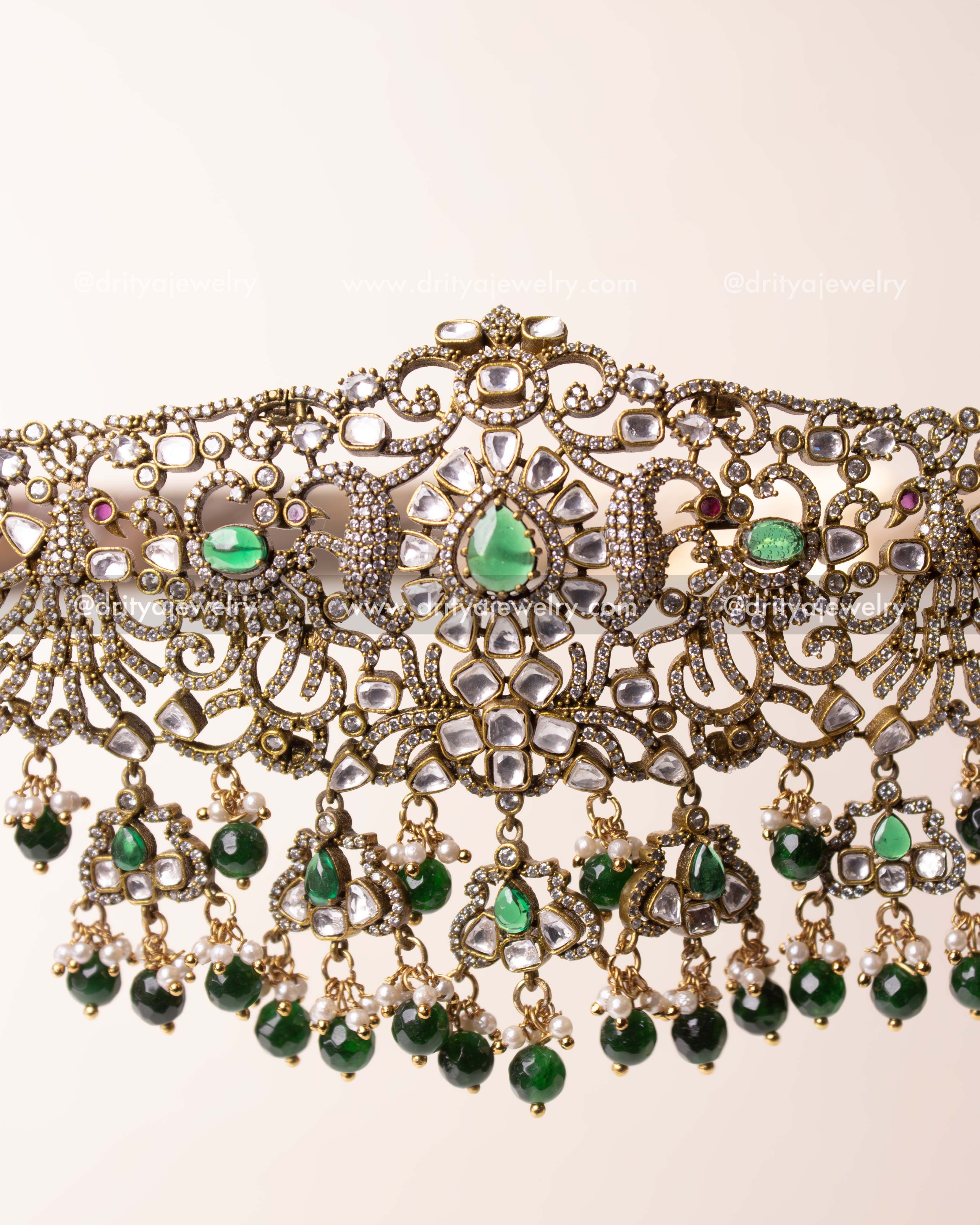 Detailed centerpiece with teardrop green kundan stone and clustered danglers.