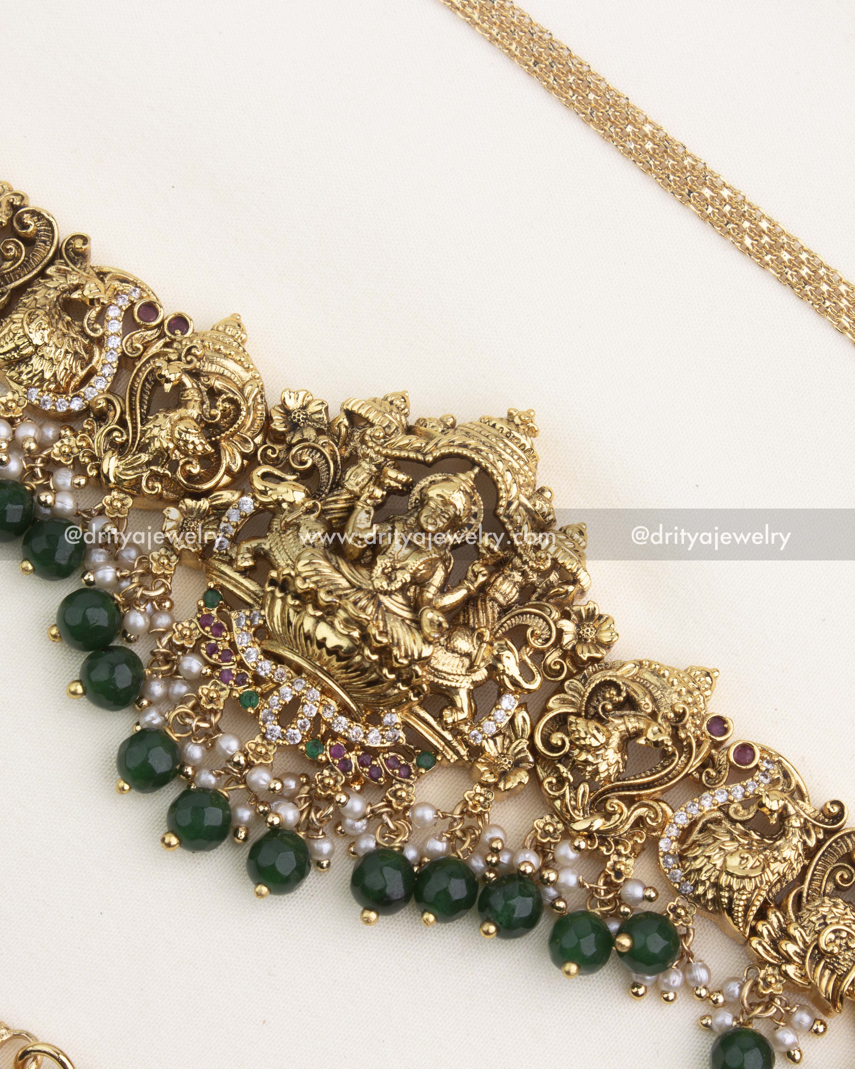 Detailed Lakshmi temple pendant with CZ stones, pearls, and green beads in antique gold finish.