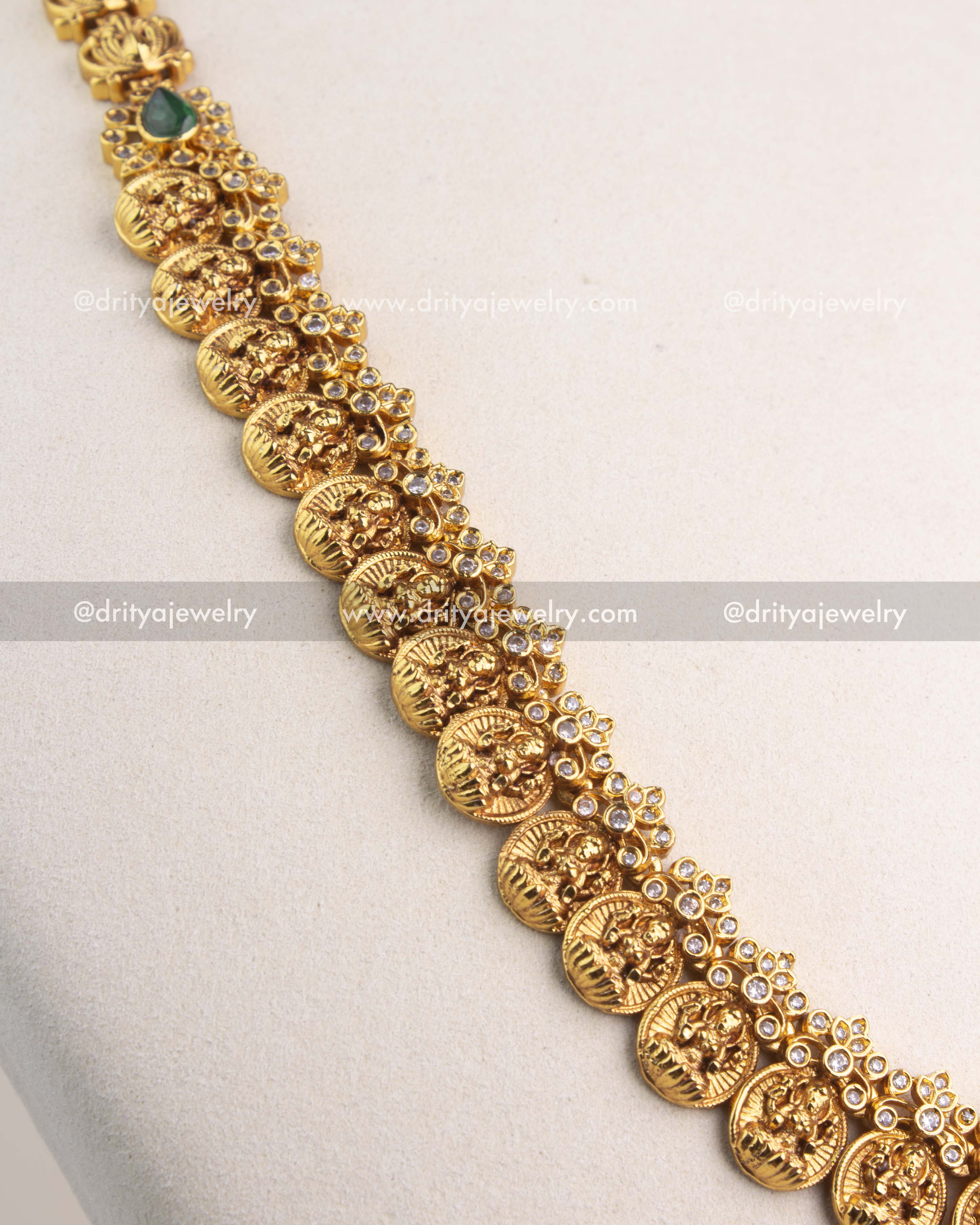 Close-up of Kasulu coin chain featuring embossed goddess motifs and green gemstone floral accent.