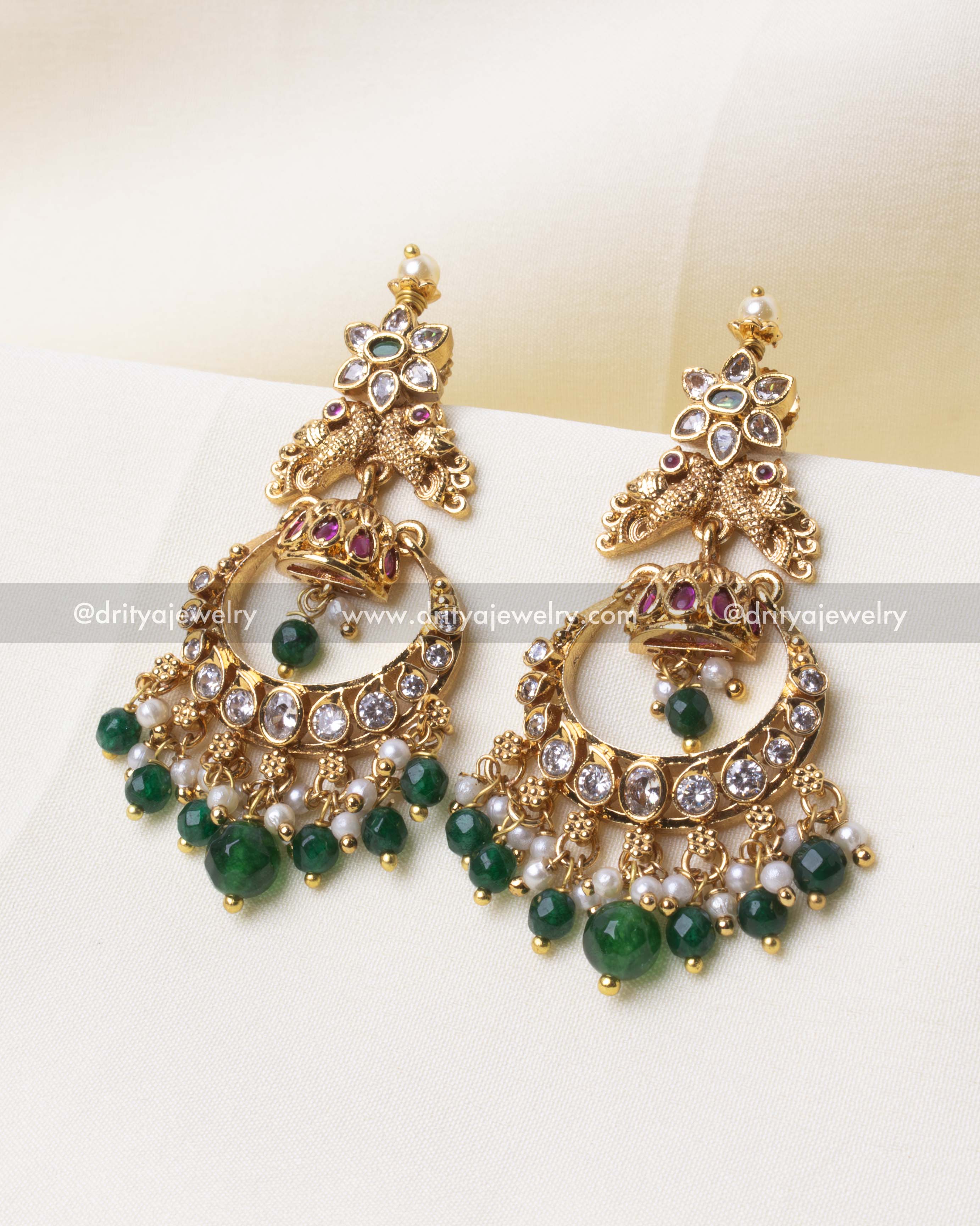 Elegant gold Chandbali earring featuring a peacock motif with green beads and sparkling stones.