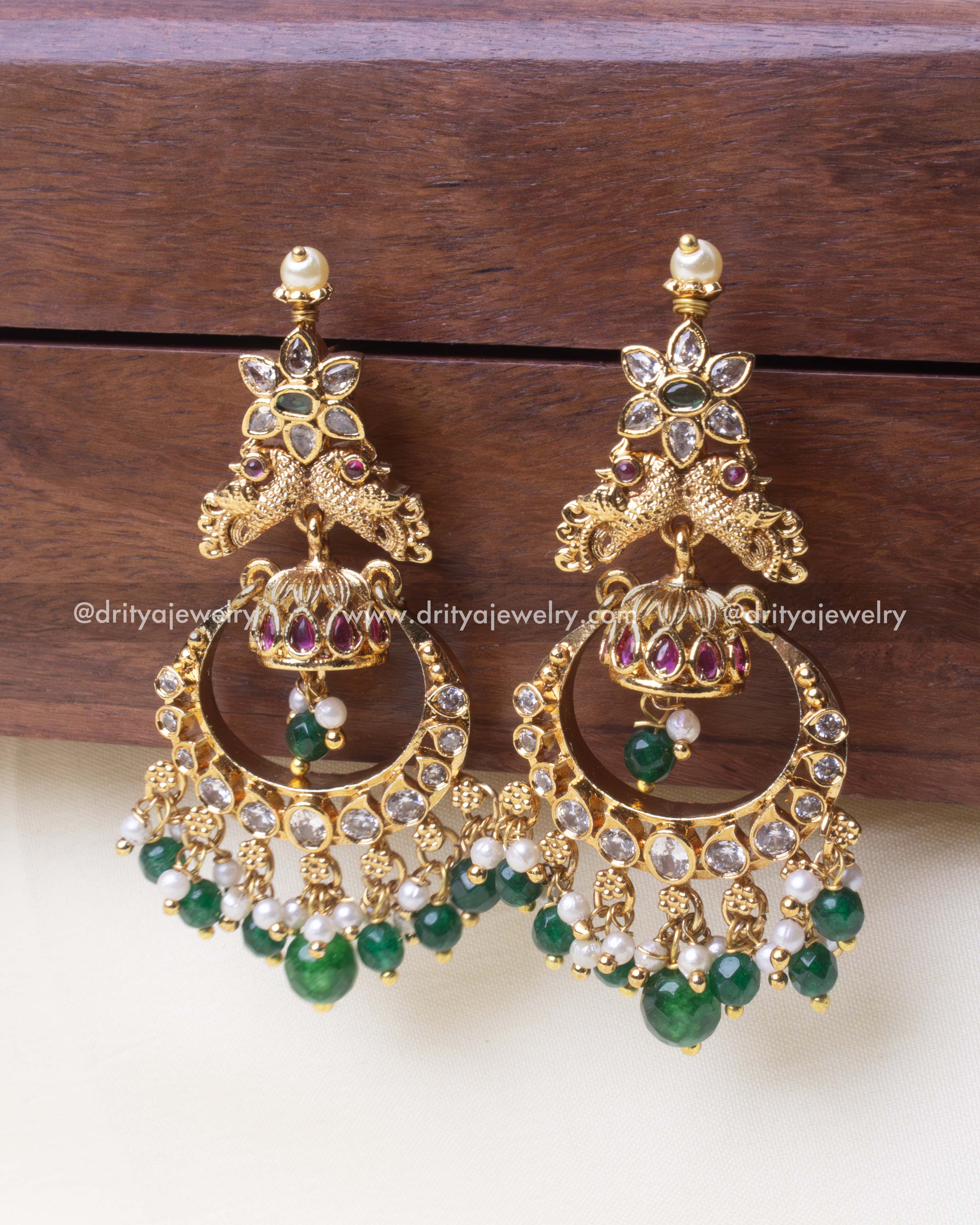 Elegant gold Chandbali earring featuring a peacock motif with green beads and sparkling stones.