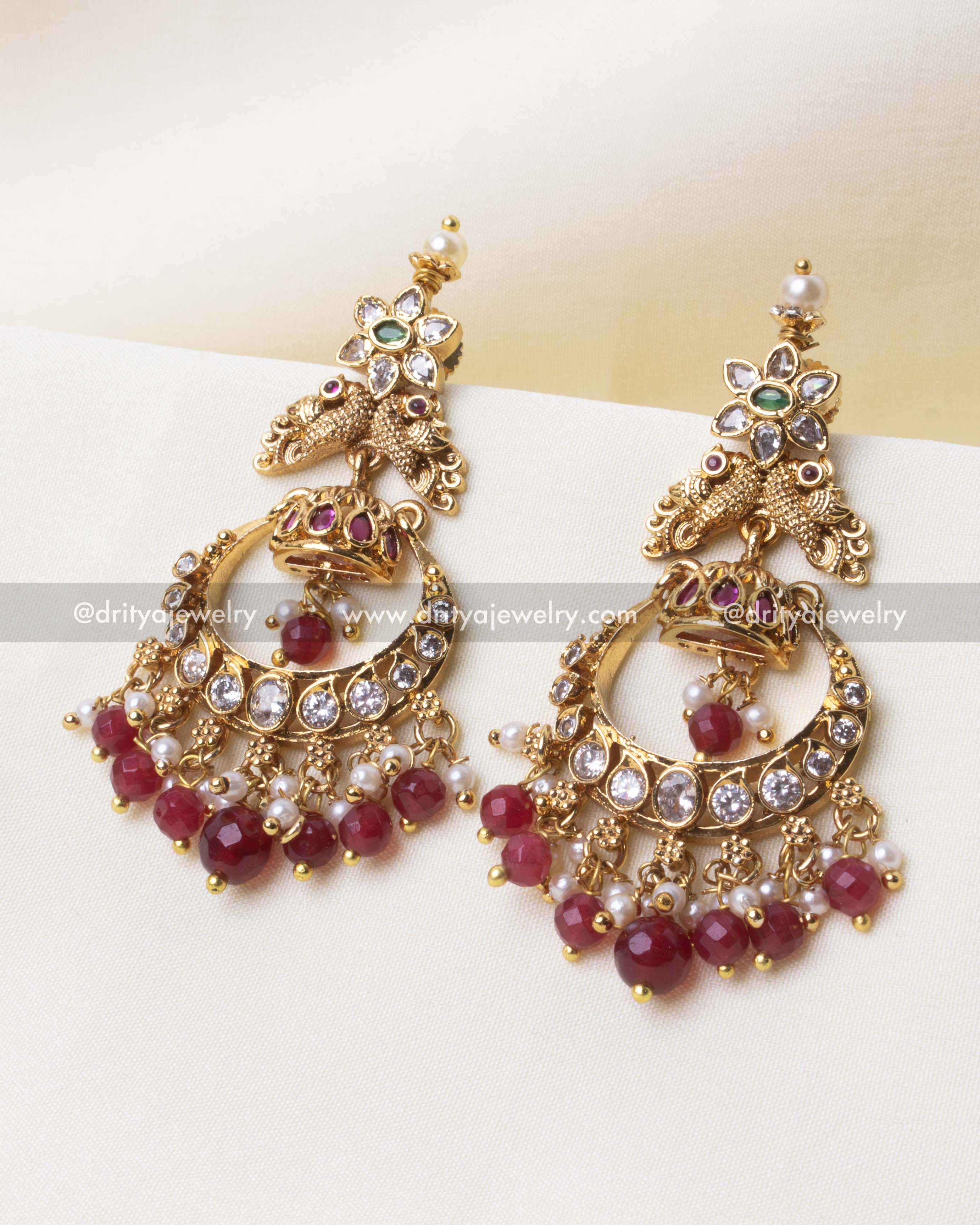 Regal gold Chandbali earring adorned with a peacock motif, ruby beads, and intricate detailing.