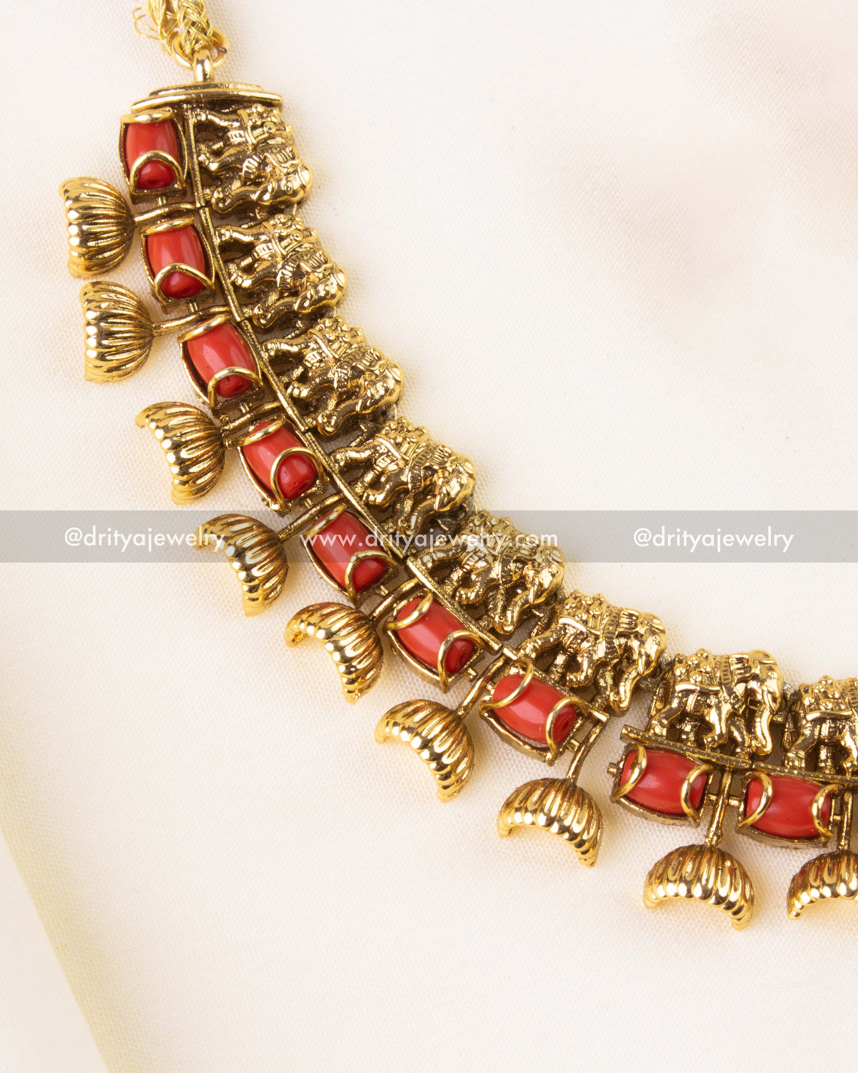 Detailed close-up of antique necklace featuring elephant motifs, red coral beads, and dome-shaped drops.