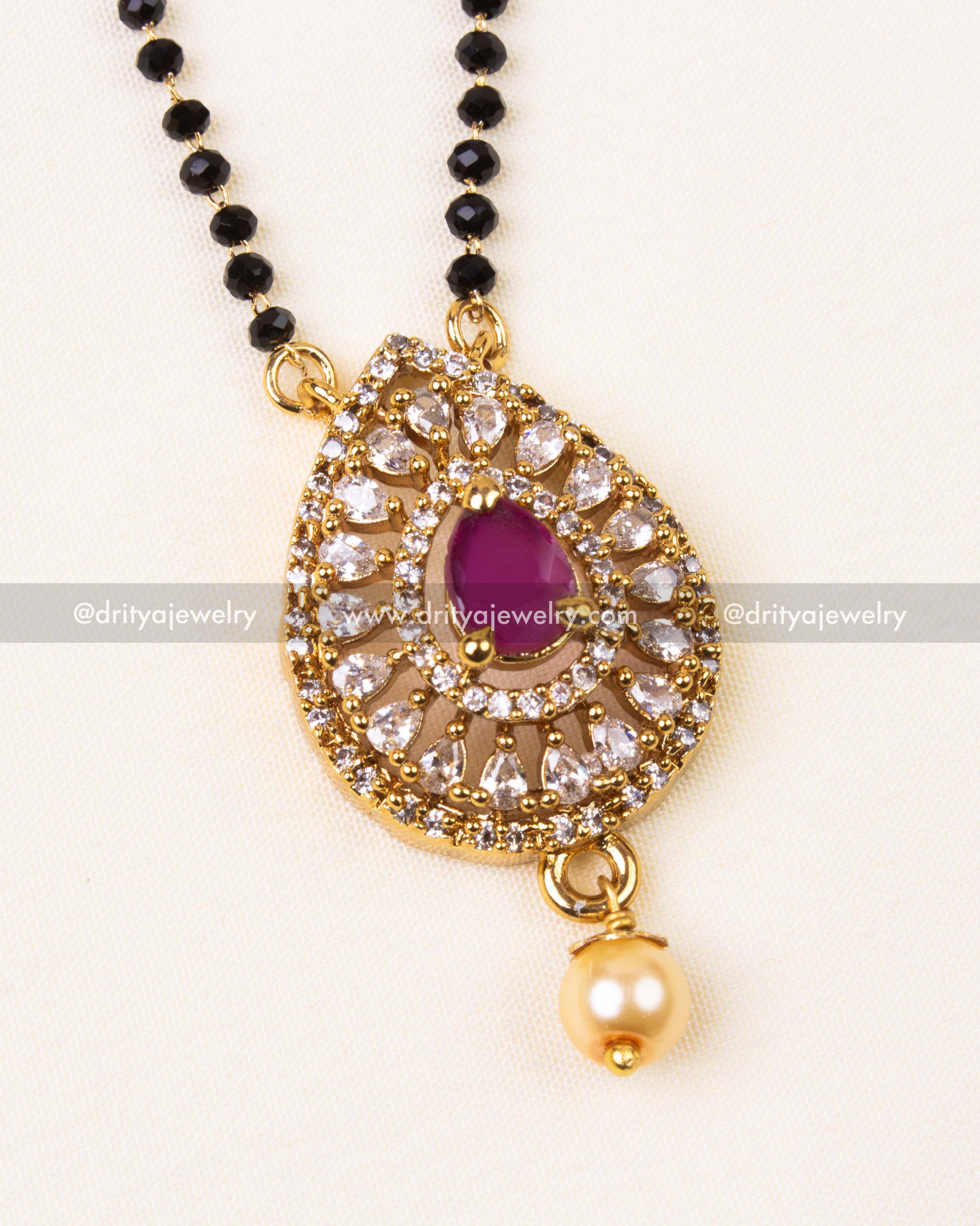 Detailed ruby red pendant with diamond-like stones and pearl drop.