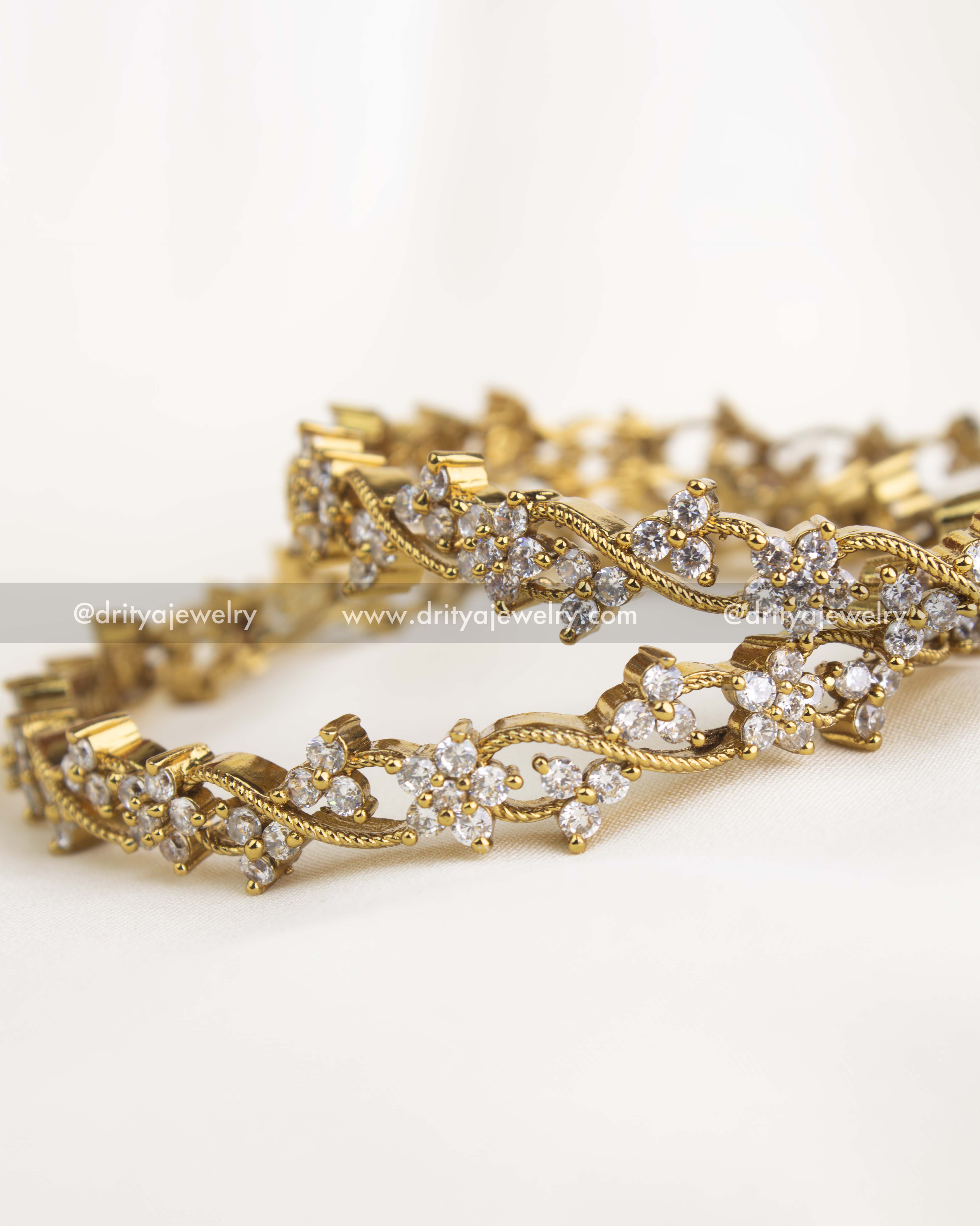 Detailed close-up showing floral motifs and sparkling AD stone clusters in gold finish.