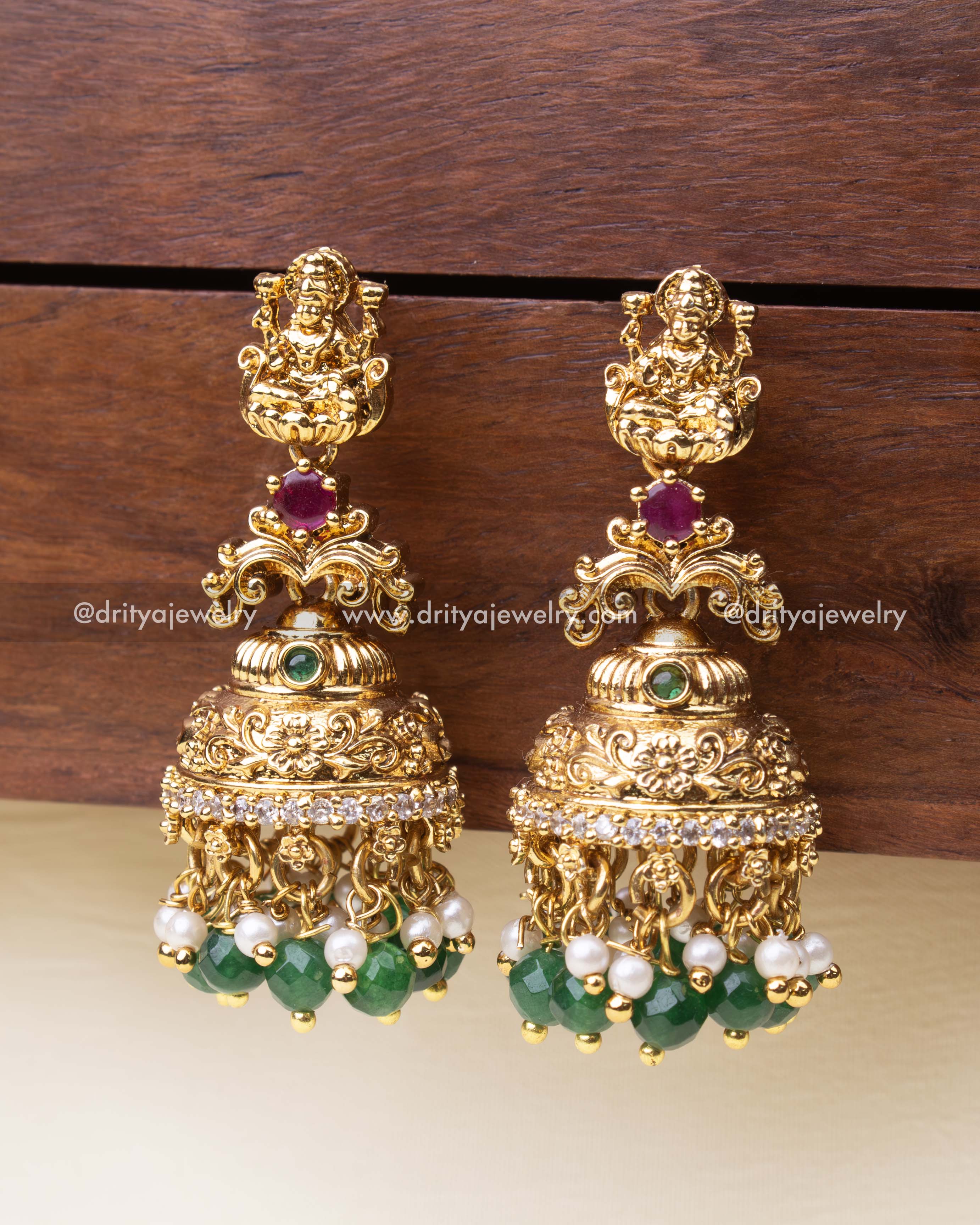 Detailed shot of temple-style jhumkas with intricate floral work and green accents.