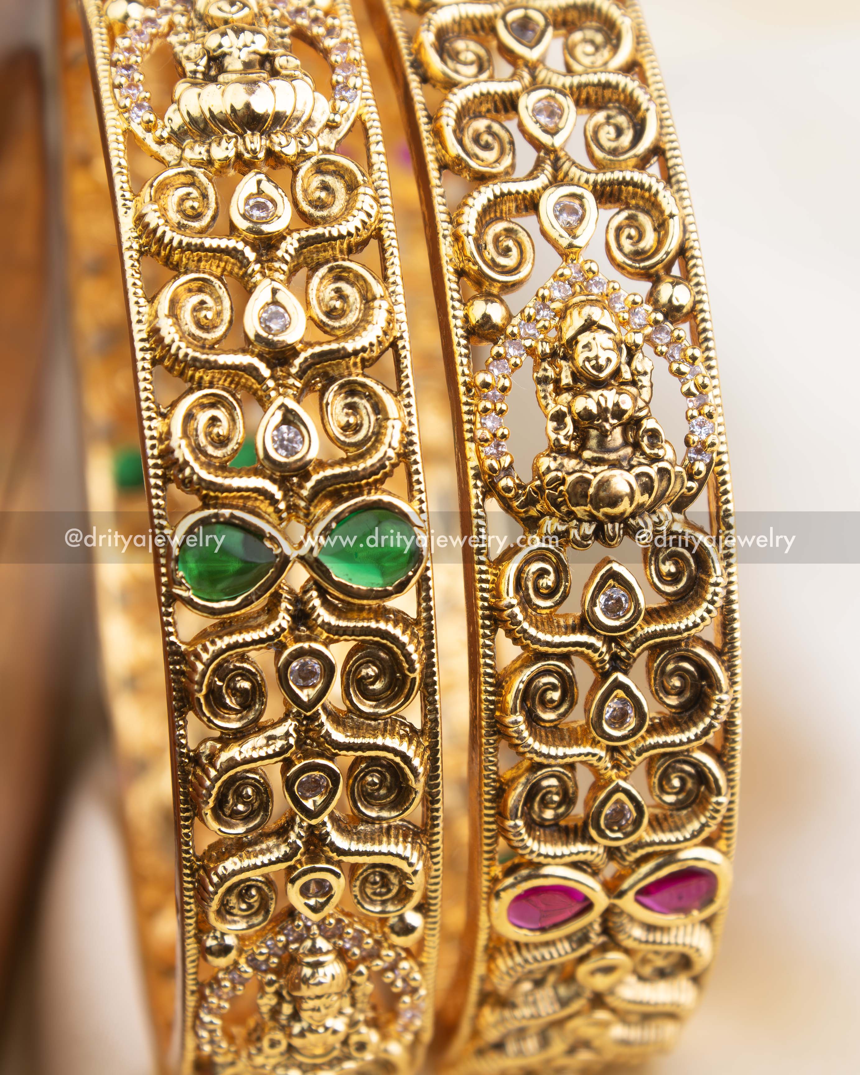 Detailed view of antique gold Nakshi bangle featuring ruby and emerald stone settings and goddess engravings.