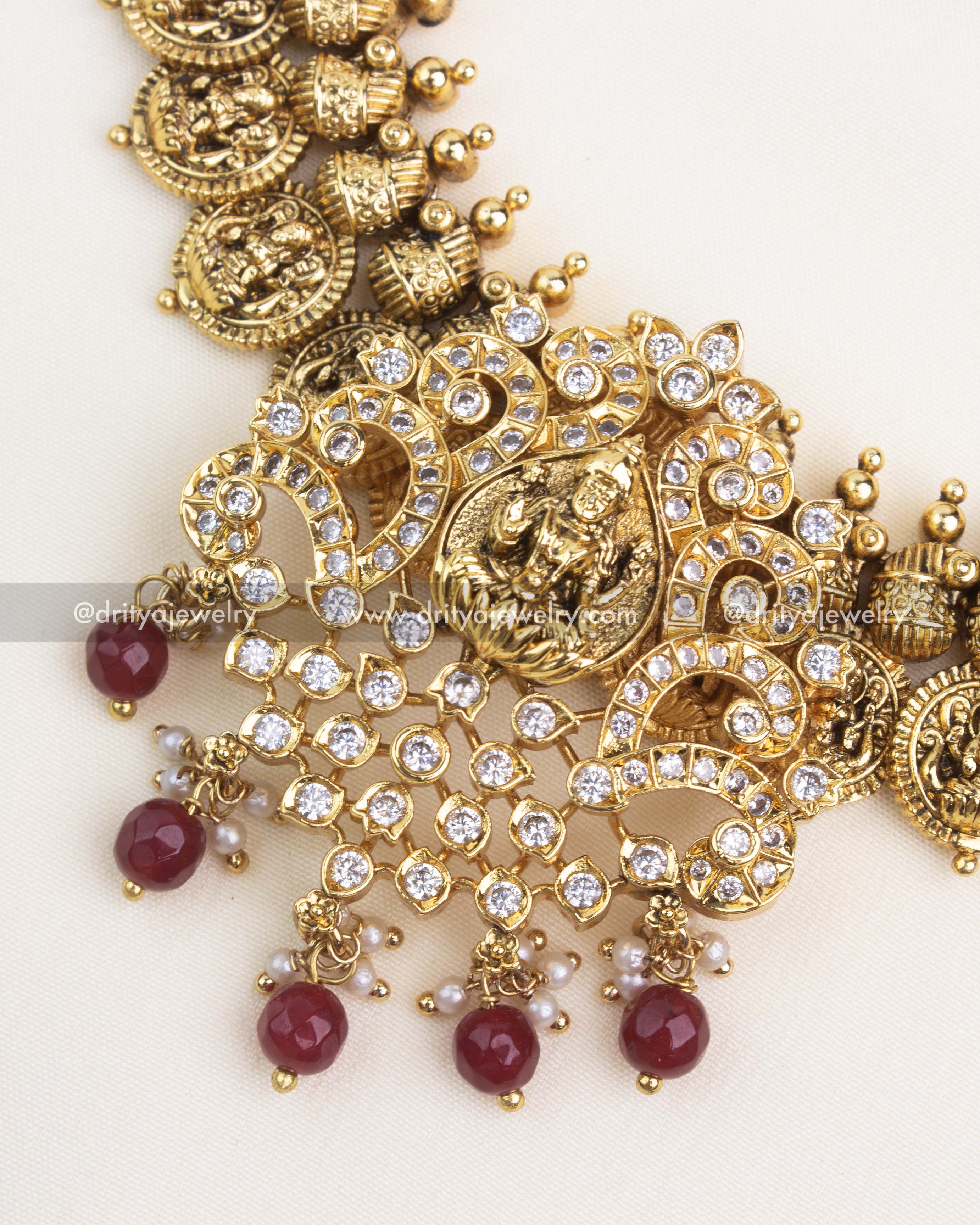 Close-up showing intricate Nakshi carving, coin-style motifs, and ruby red beads with AD stone highlights.