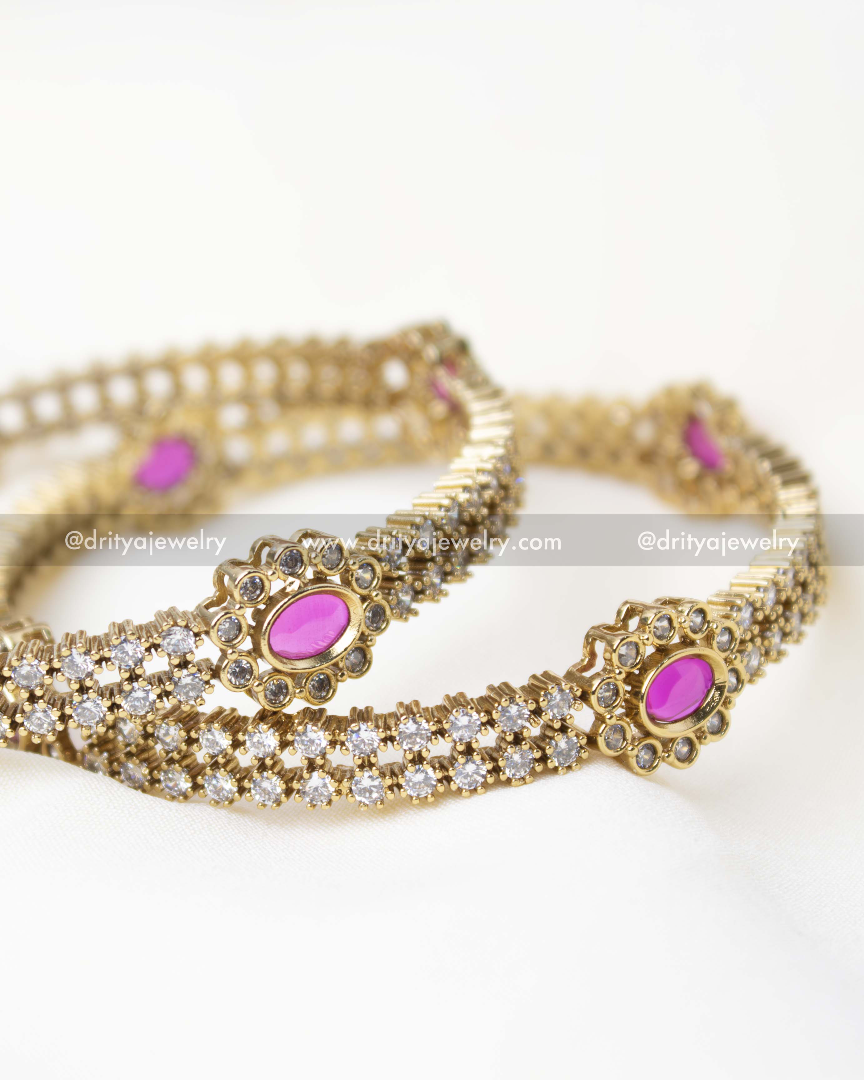 Detailed view of a gold-plated bangle with pink stone and CZ embellishments.