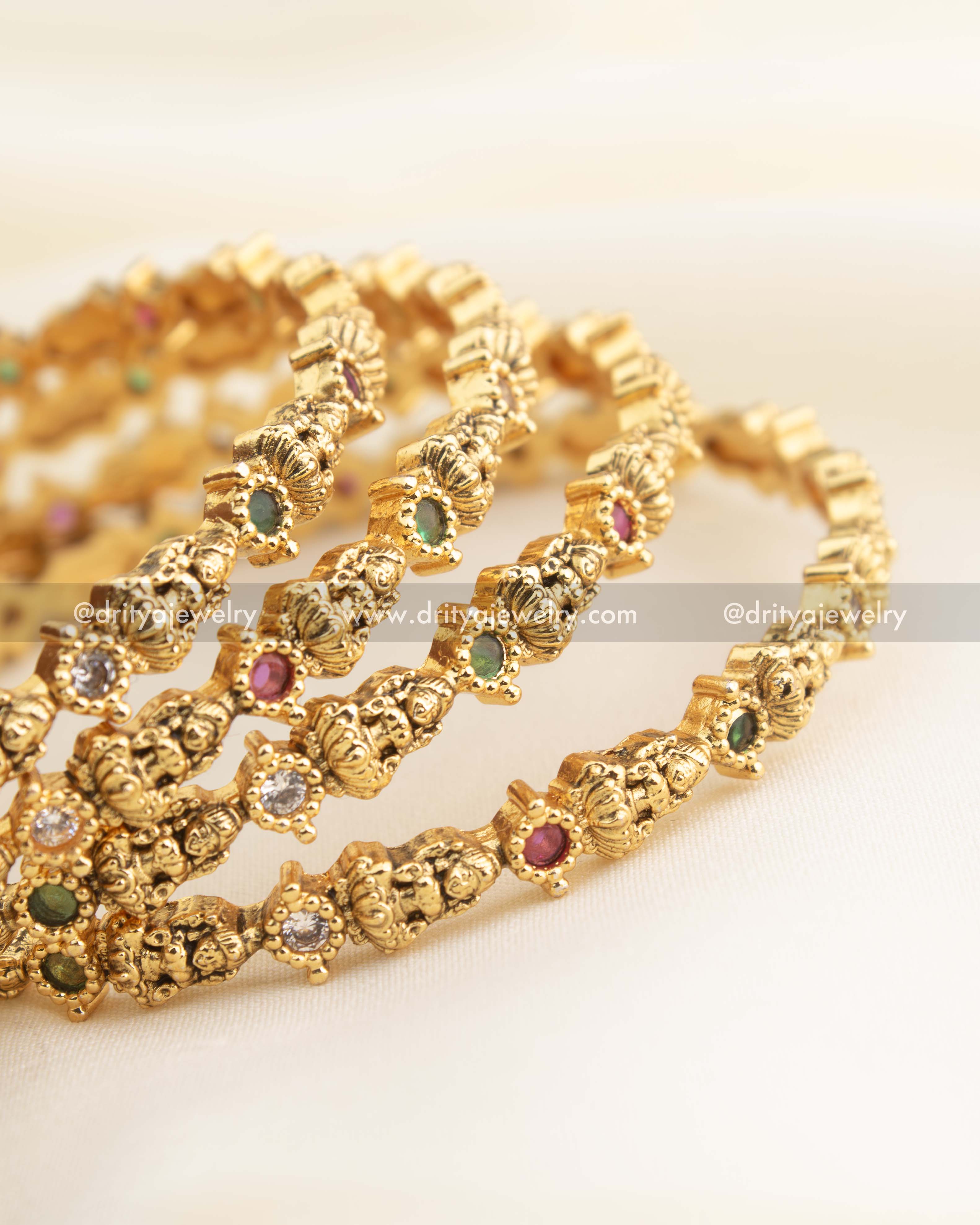 Intricately designed Lakshmi bangles with CZ stones and antique gold polish.
