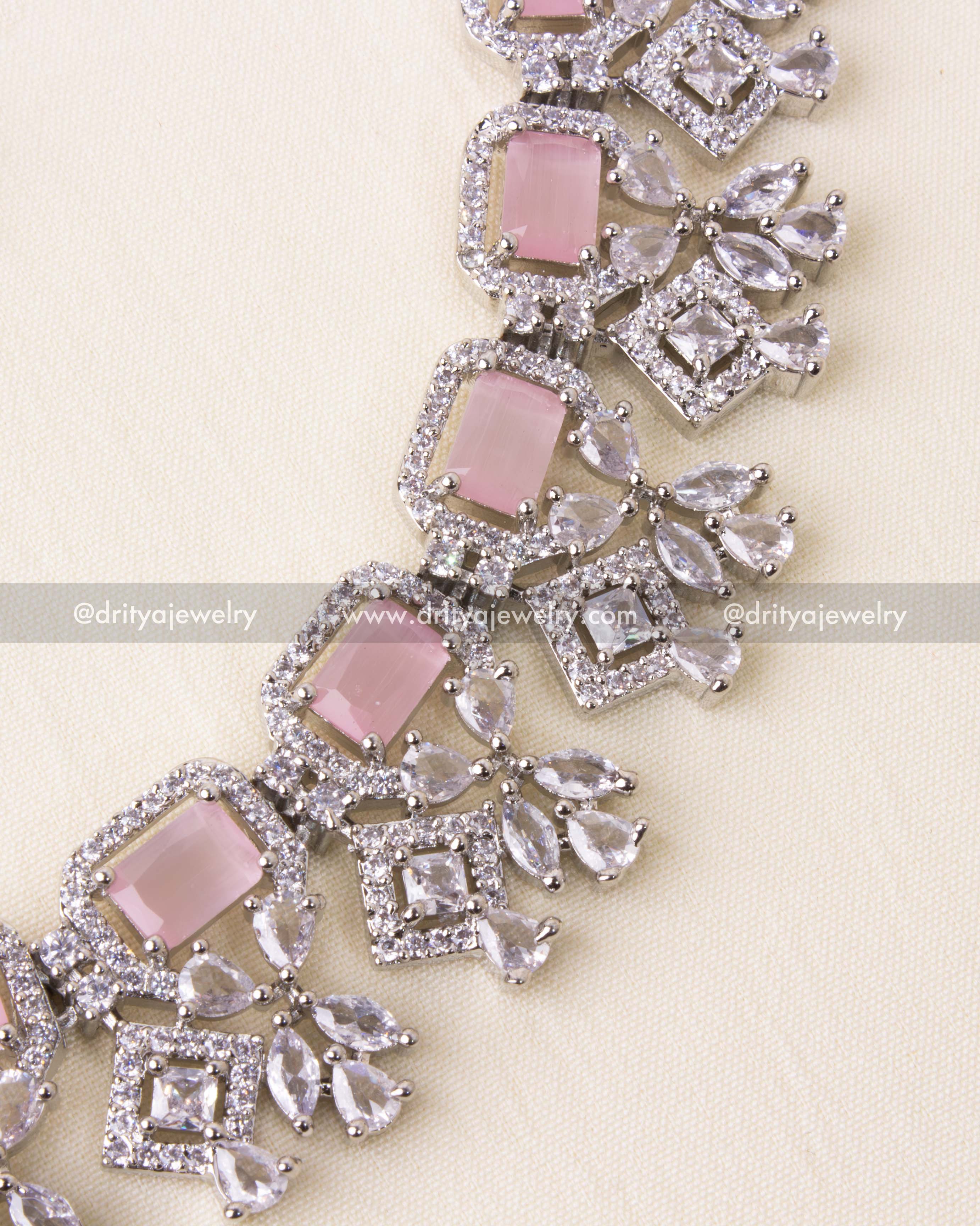 Detailed craftsmanship of zircon squares and teardrop accents with blush pink stones.