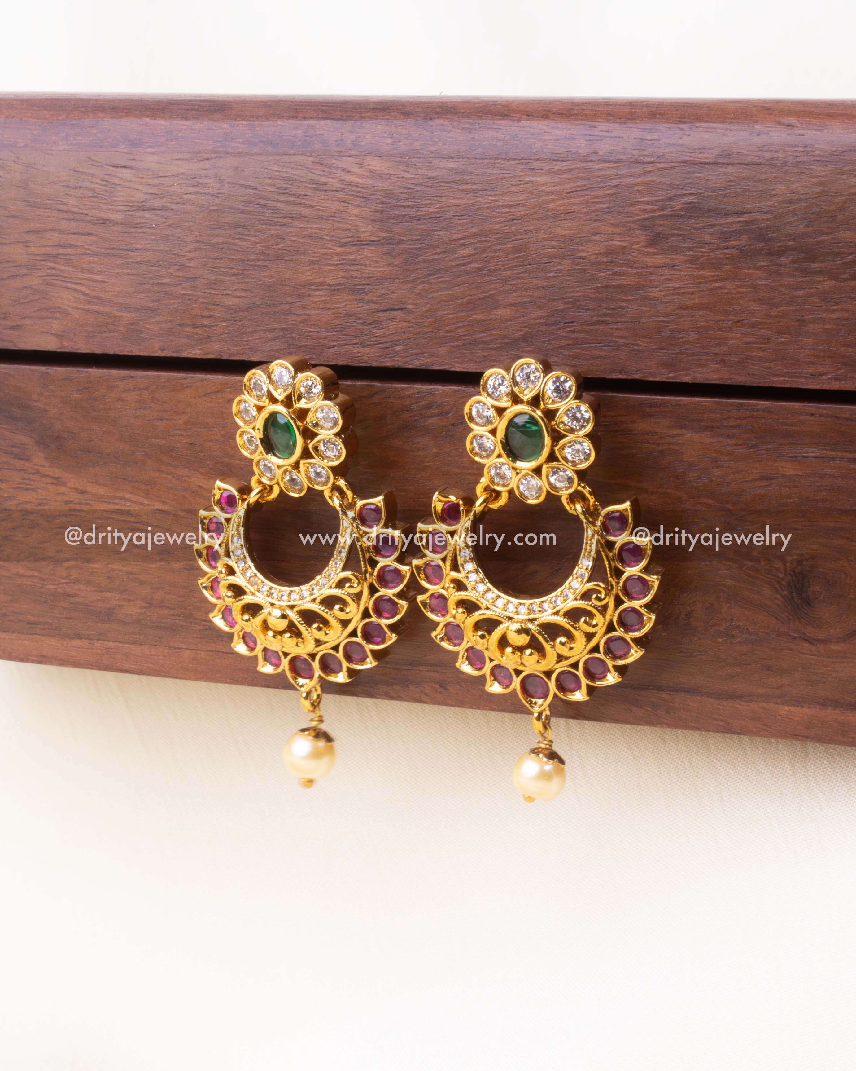 Detailed view of crescent-shaped Chandbali with ruby-toned stones and pearl.