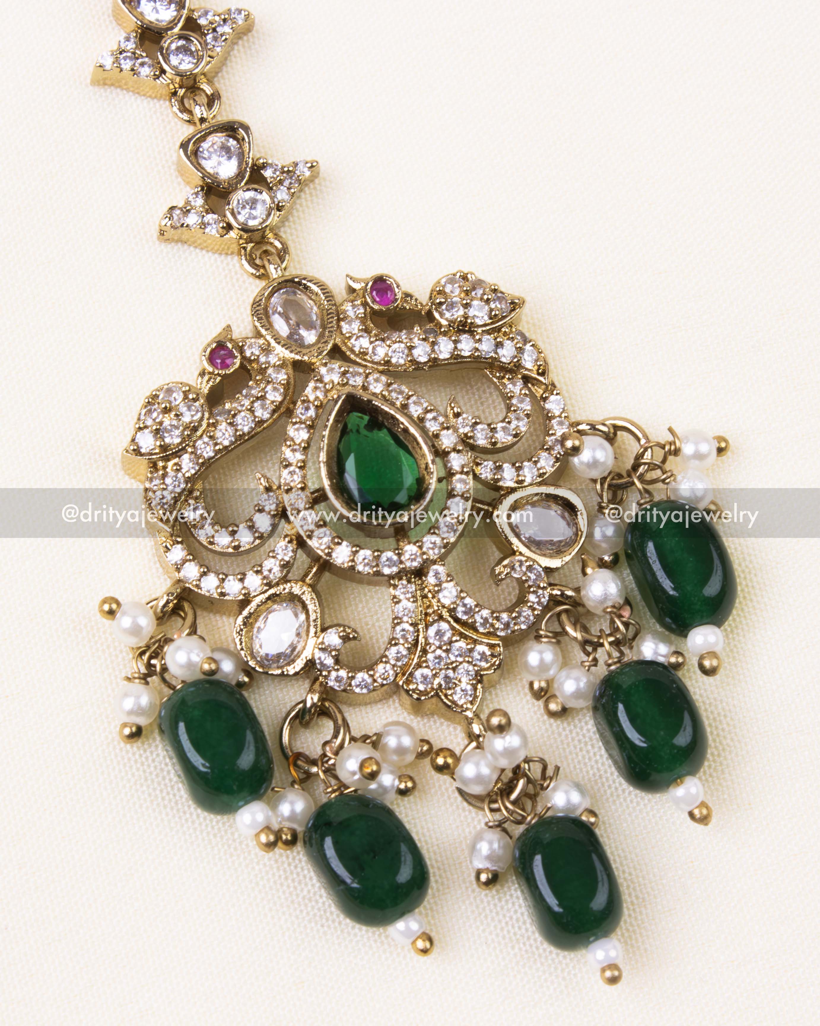 Detailed view of green and gold maang tikka with Victorian floral design.