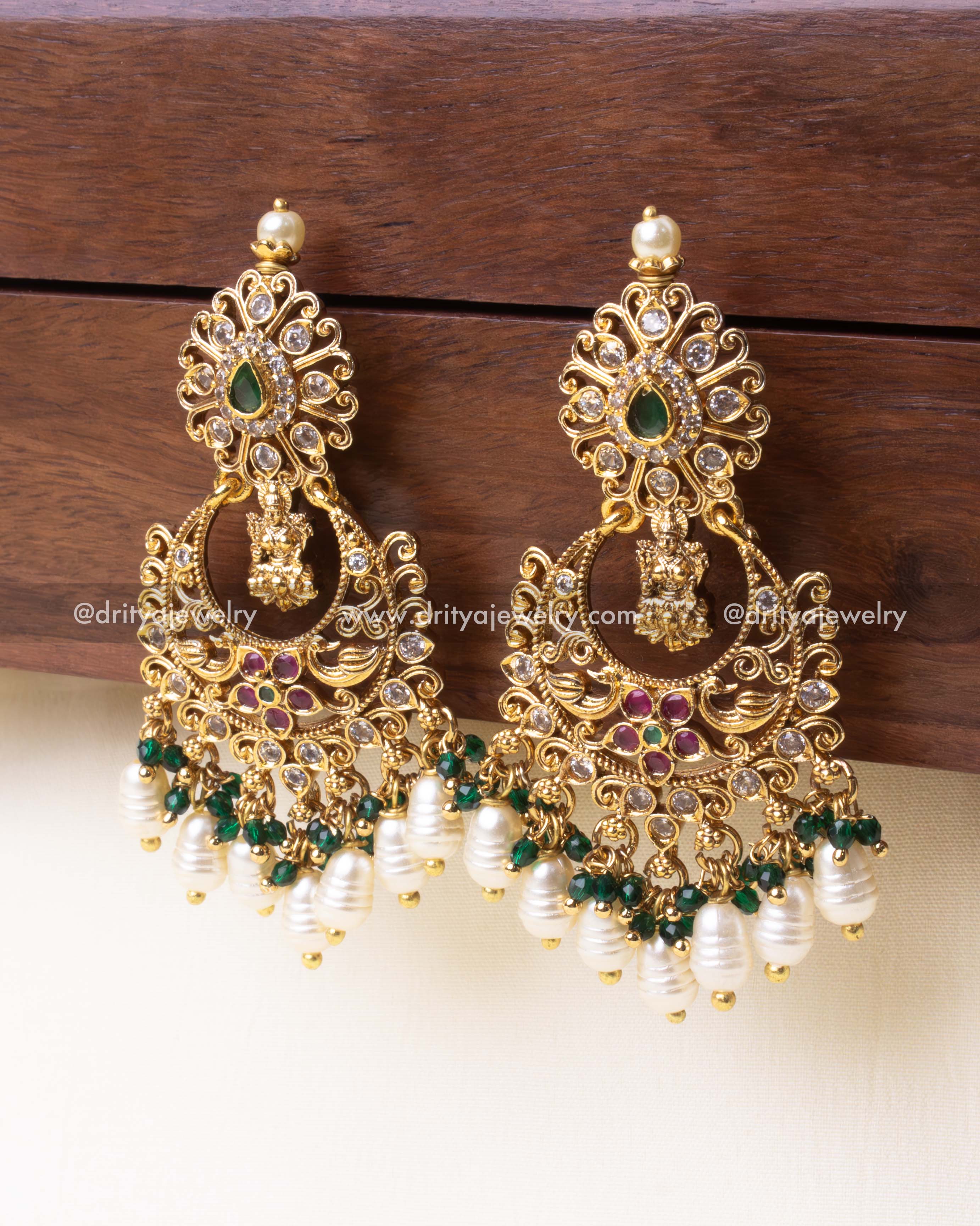 Detailed close-up of traditional green Chandbali earrings showcasing handcrafted carvings and pearl beadwork.