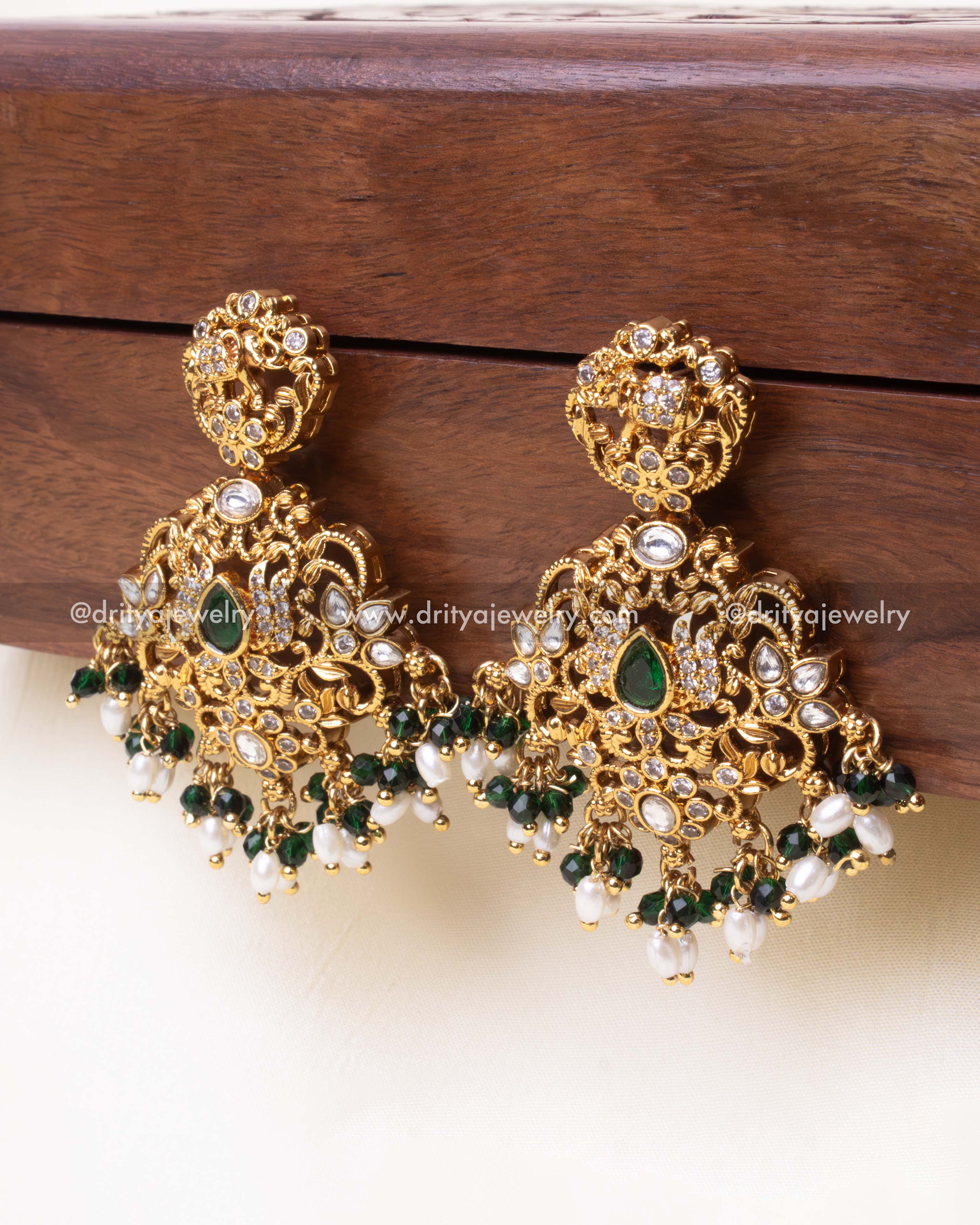 Detailed view of handcrafted elephant motif dangler earrings with pearl embellishments and green accents.