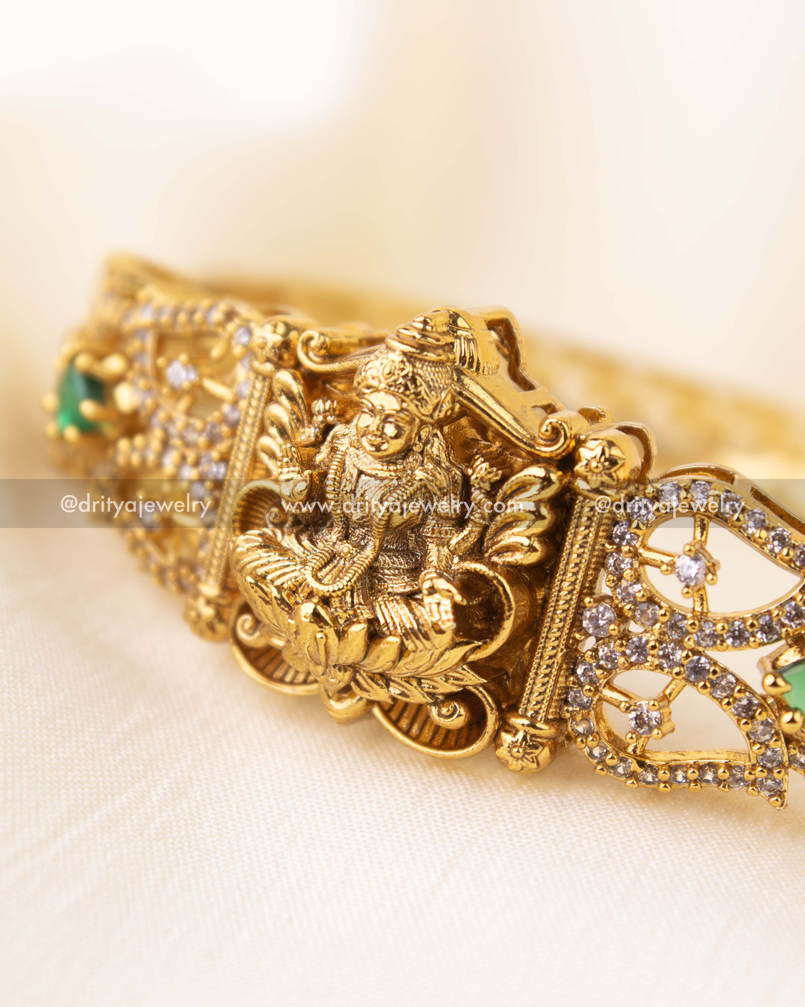 Detailed view of Nakshi kada featuring CZs and emerald green stonework