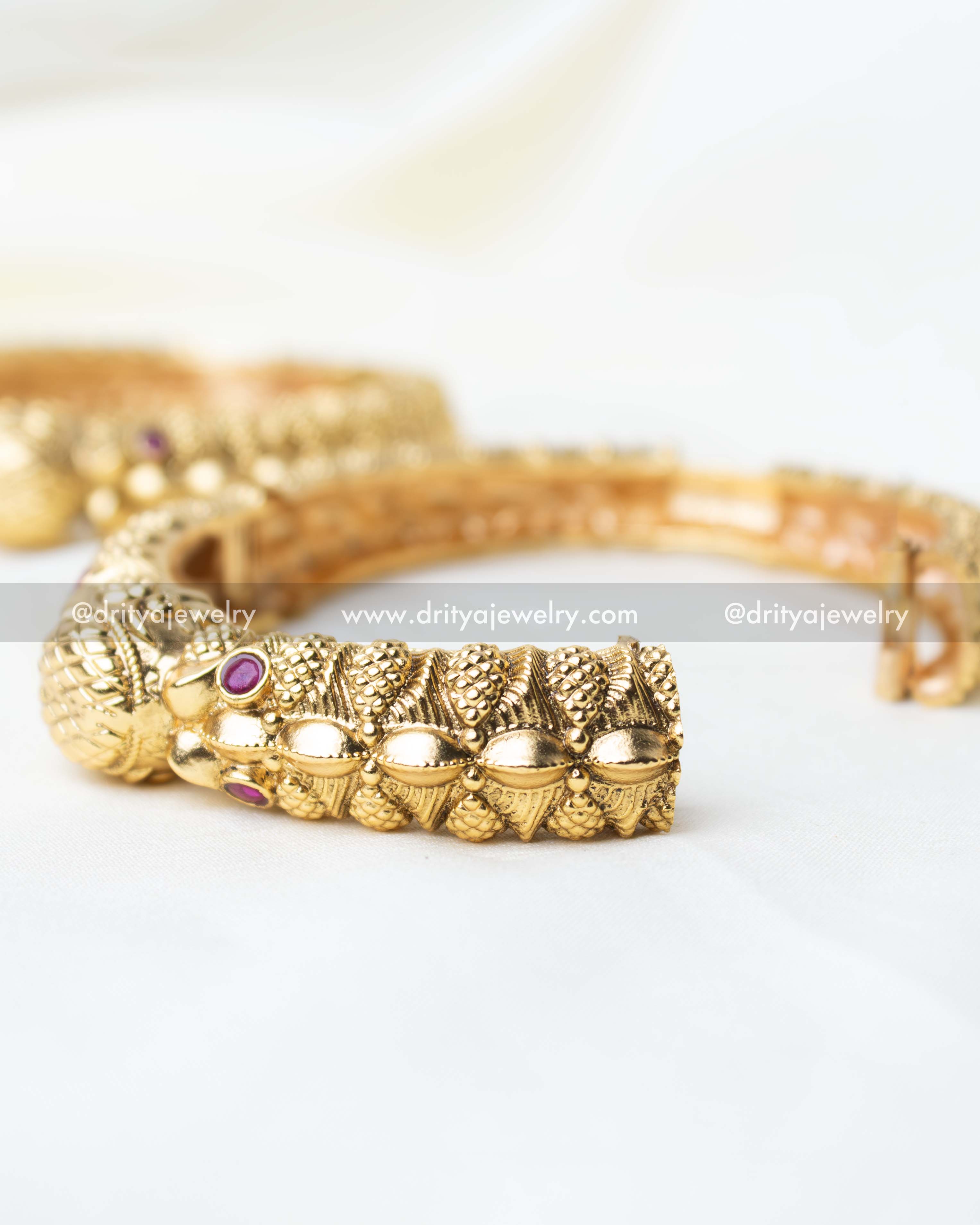 Detailed view of the openable kada with traditional carvings and ruby embellishments.