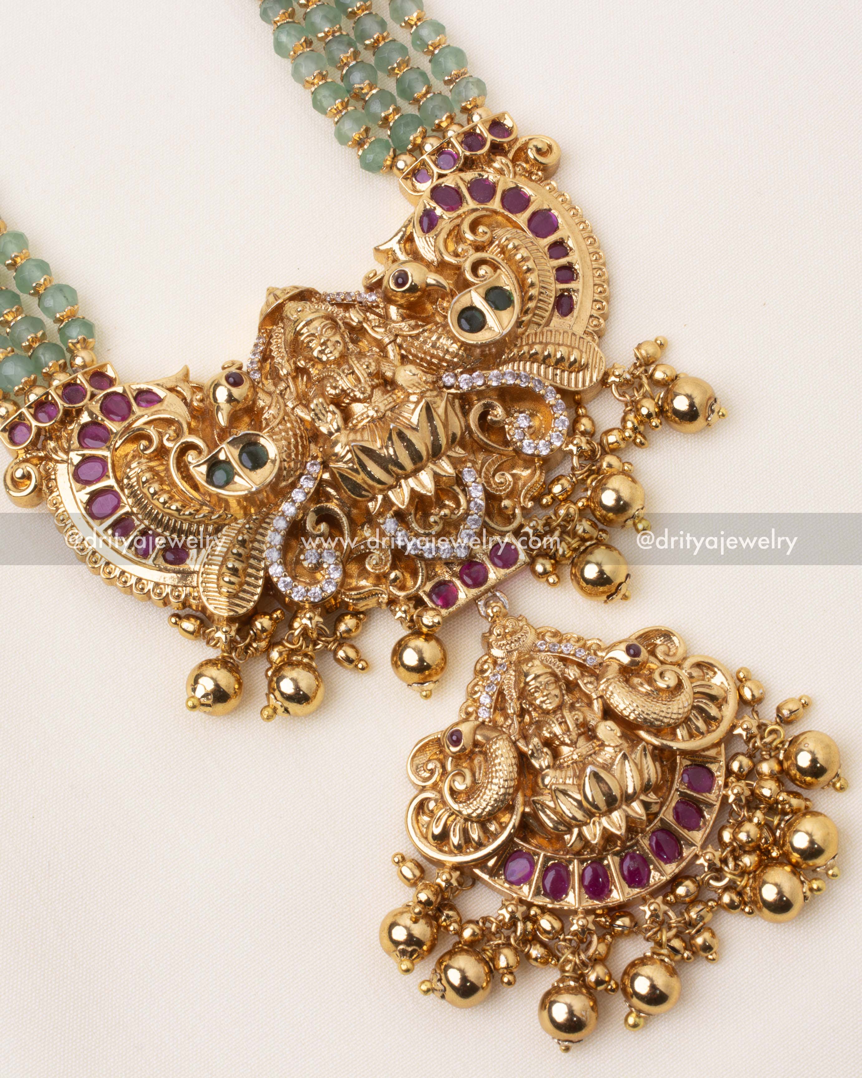 Detailed view of the intricately crafted Lakshmi Devi pendant with ruby red and CZ stone embellishments.