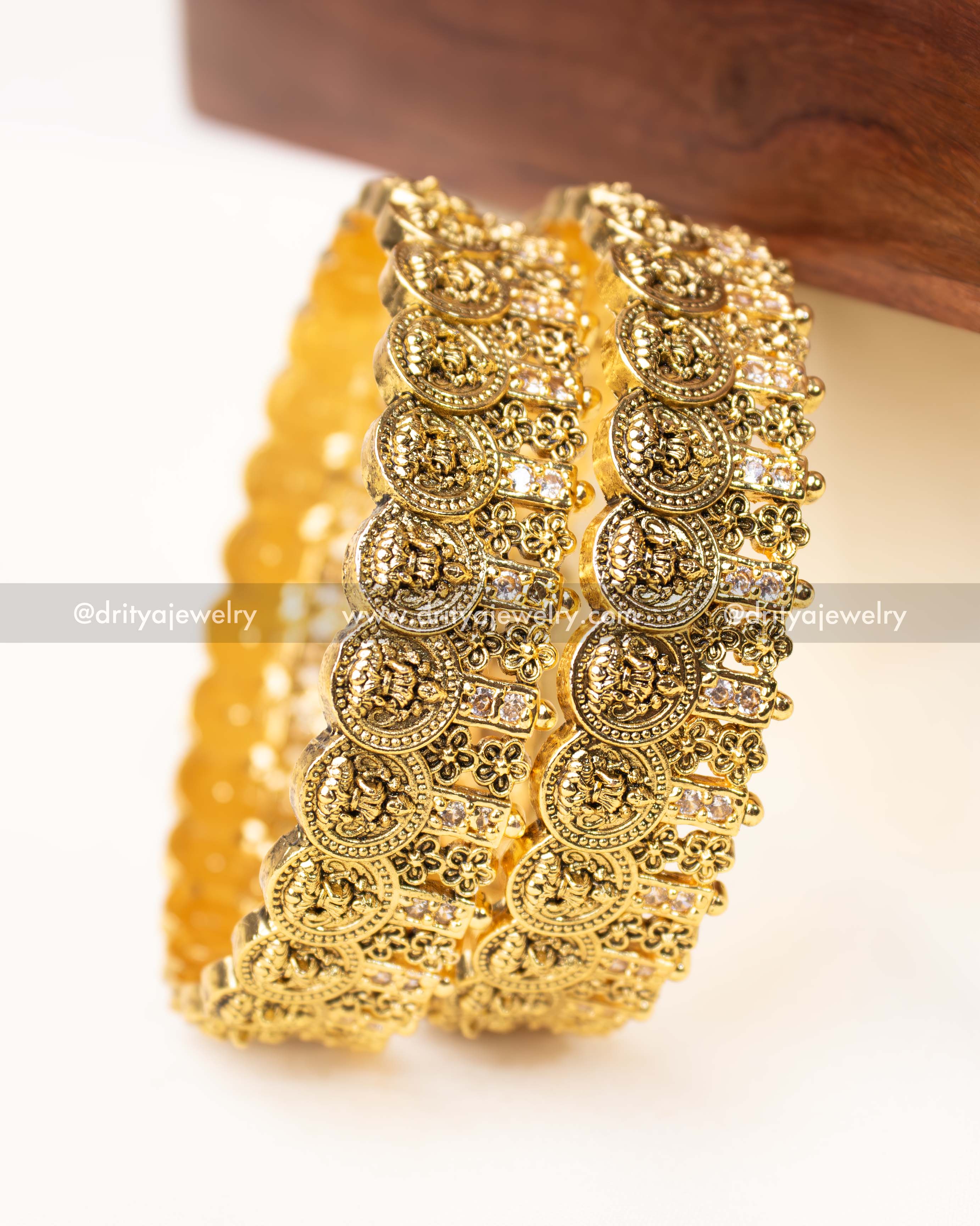 Detailed view of temple-inspired Nakshi bangles with intricate carvings and CZ stone embellishments.