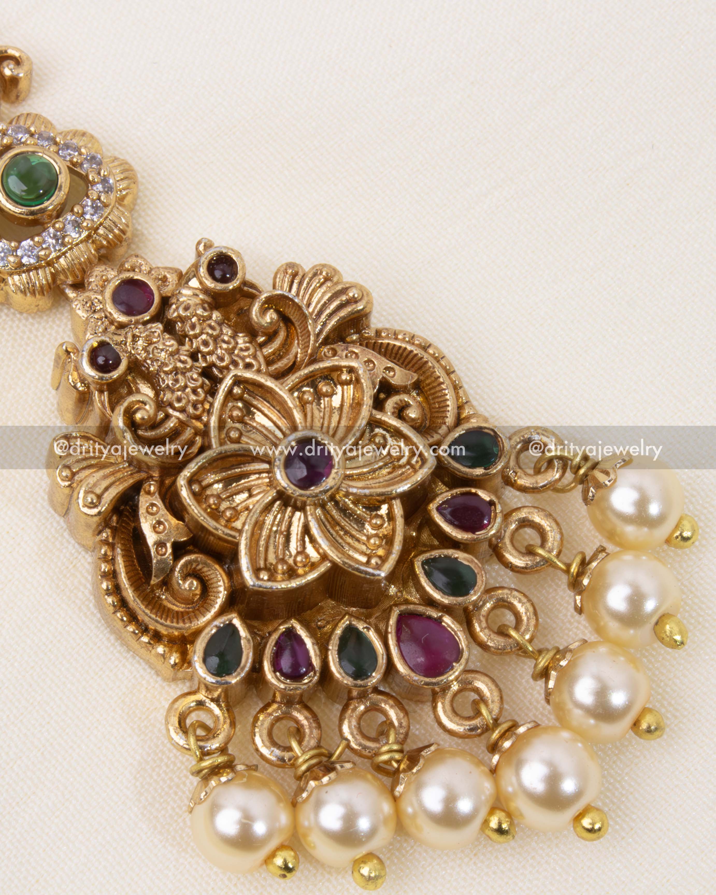 A close-up showcasing intricate temple-style carvings, pearls, and floral embellishments.