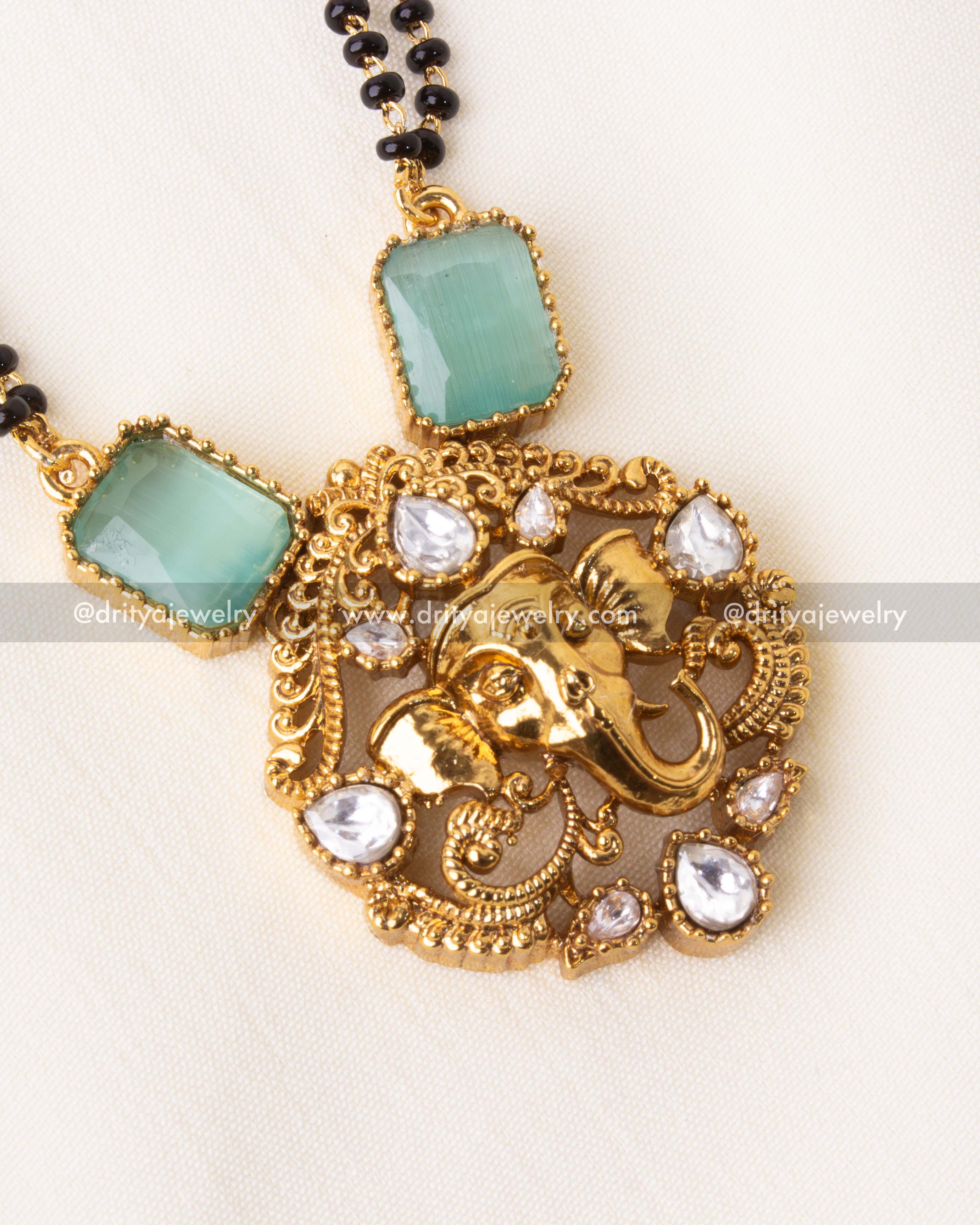 Detailed view of Ganesha pendant with mint green stones and American diamonds on black beads necklace.