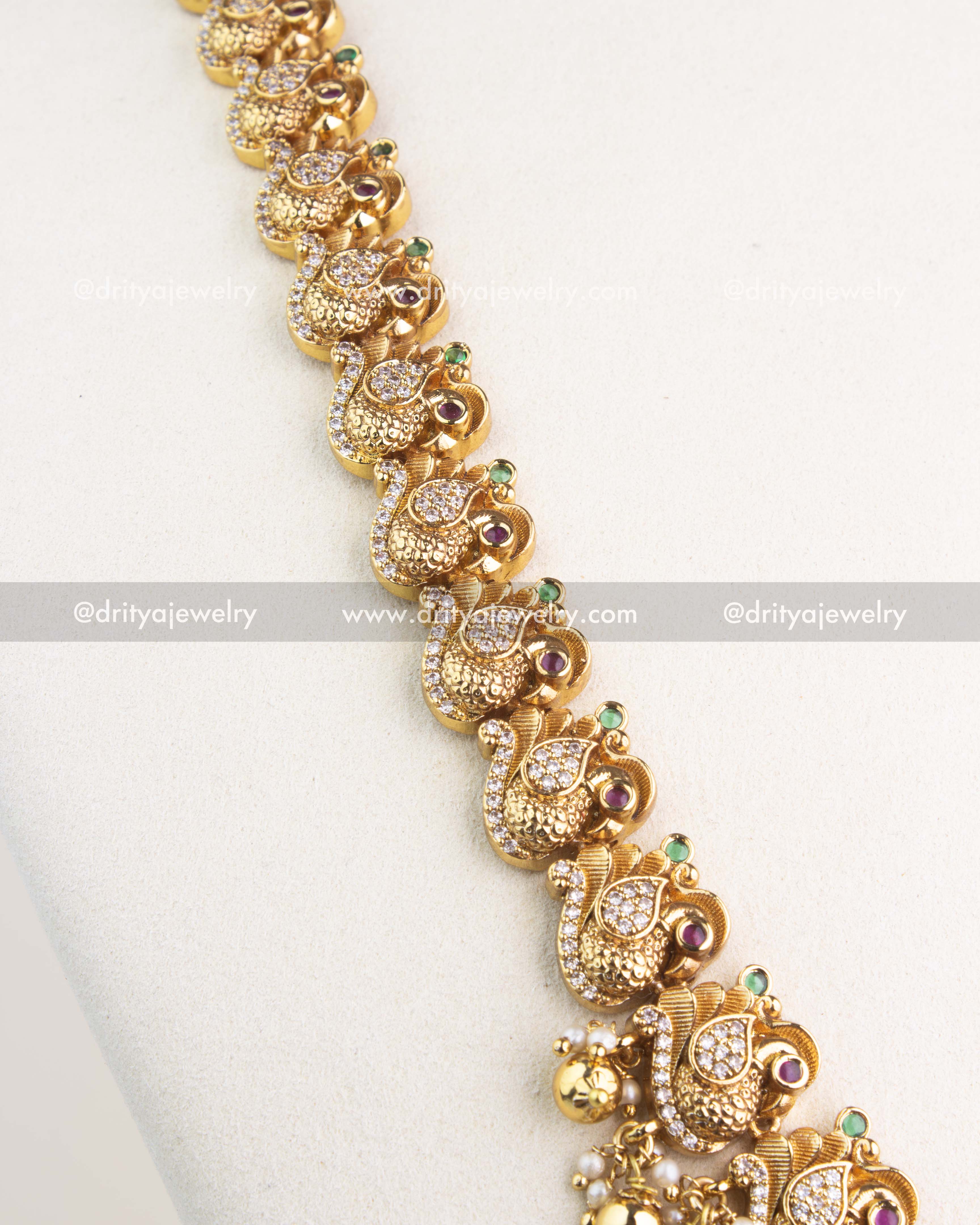 Detailed peacock motif chain with ruby and emerald highlights in temple jewelry long necklace.