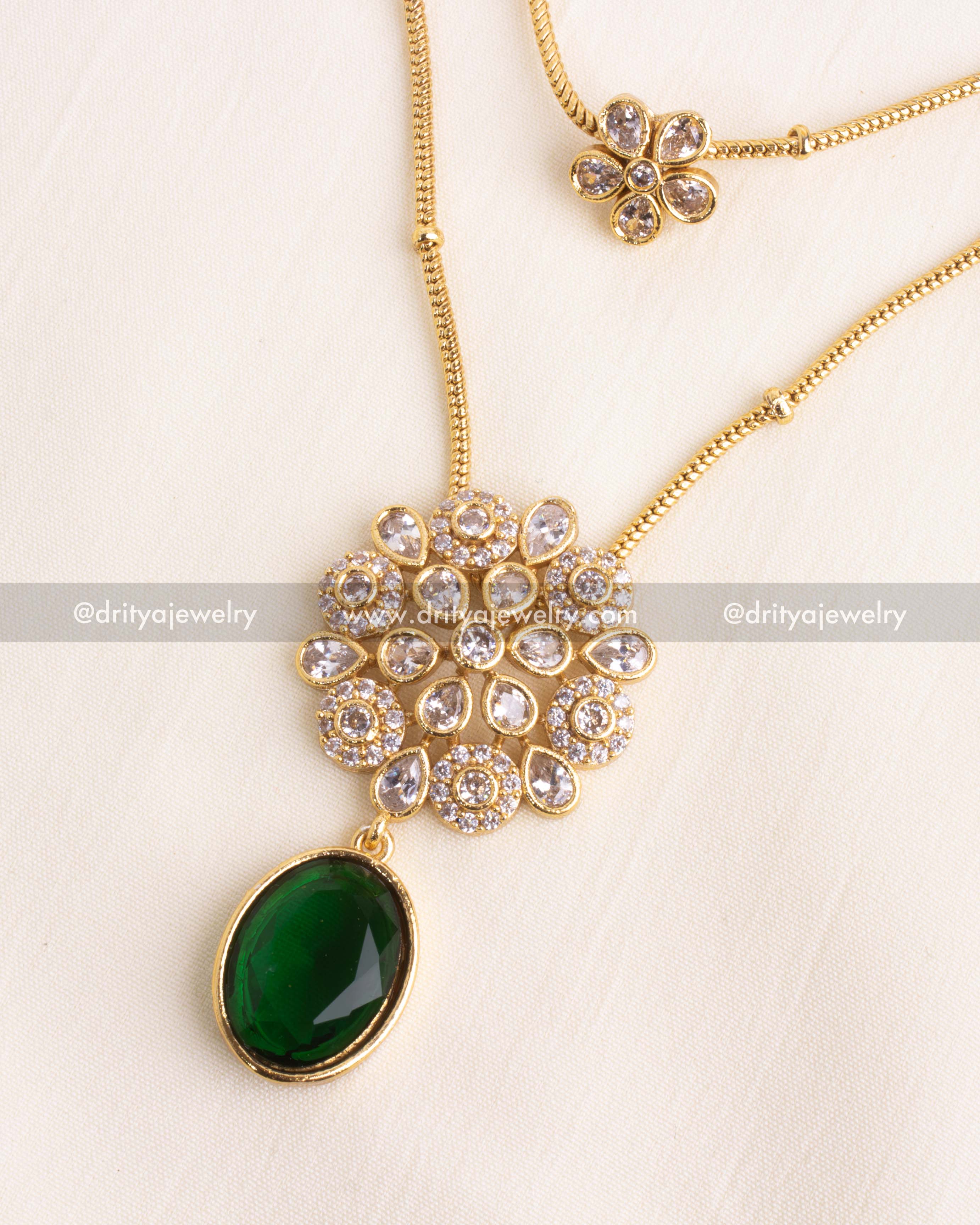 Detailed view of emerald green pendant with floral kundan centerpiece.