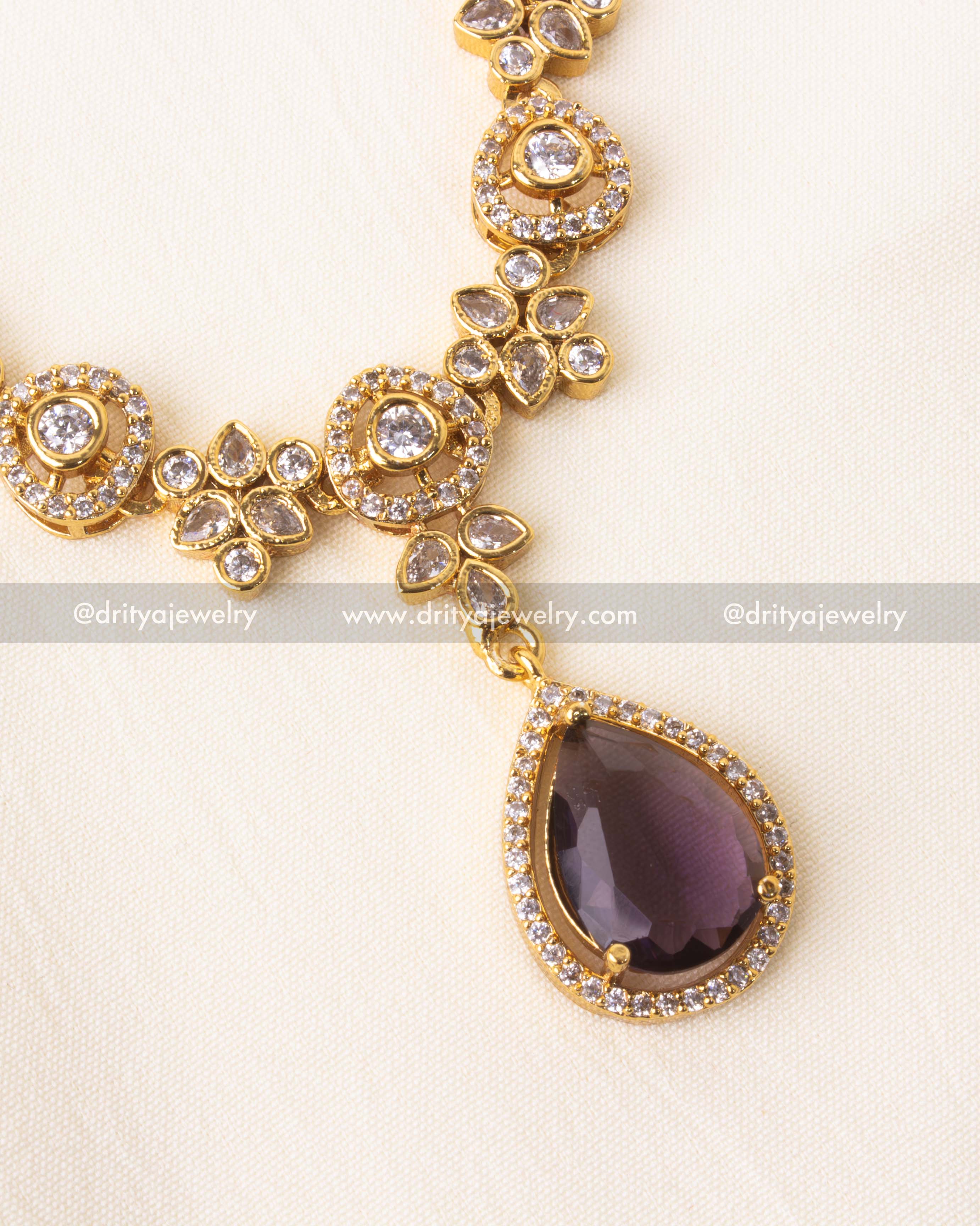 Intricate gold-plated necklace with purple teardrop stone.