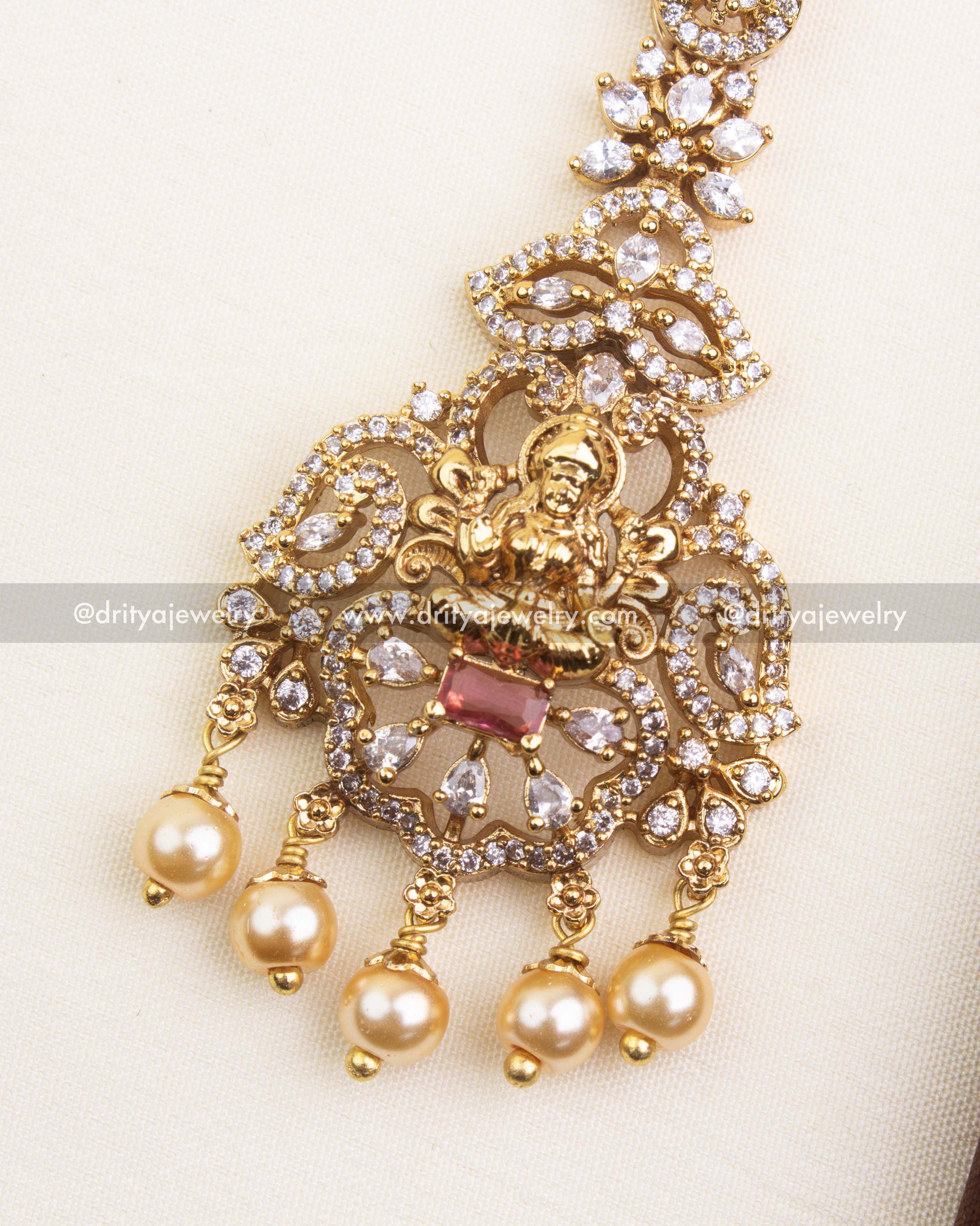 Detailed view of temple-style red maang tikka with goddess motif, CZ stones, and pearl danglers.