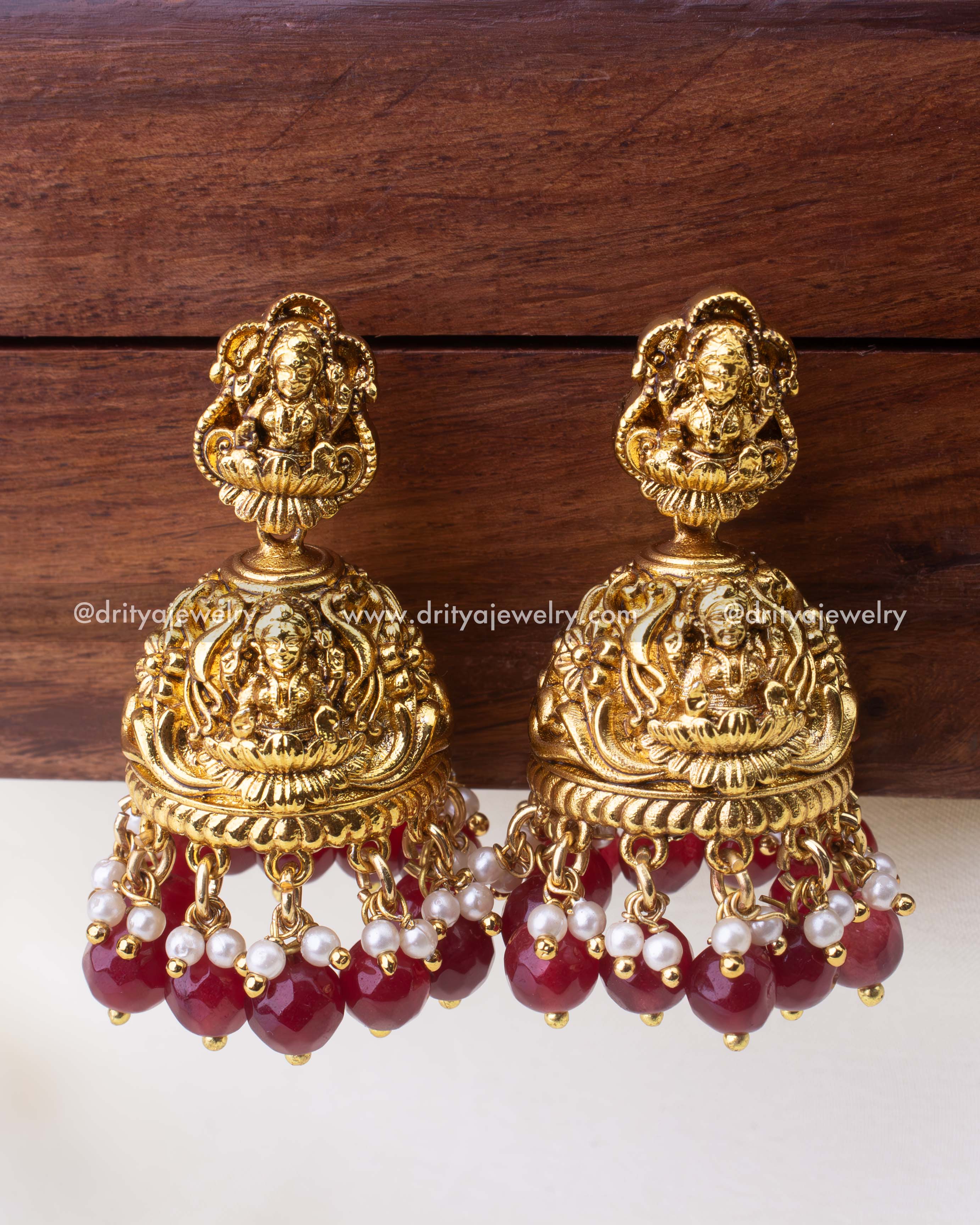 Traditional temple jewelry Jhumkas with ruby-red bead drops, pearls, and antique finish.