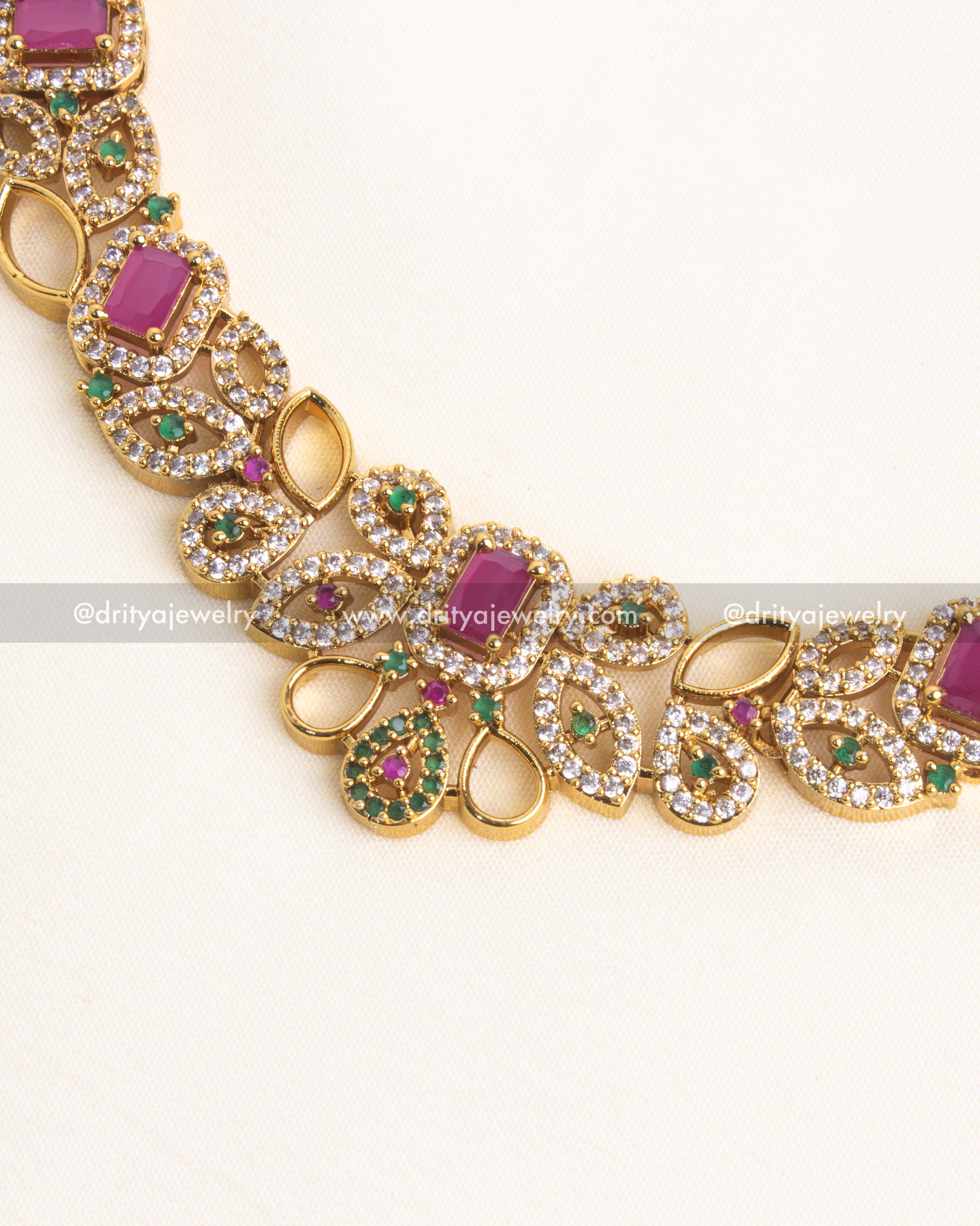 Detailed view of a gold-plated short necklace with pink stones and intricate floral motifs.