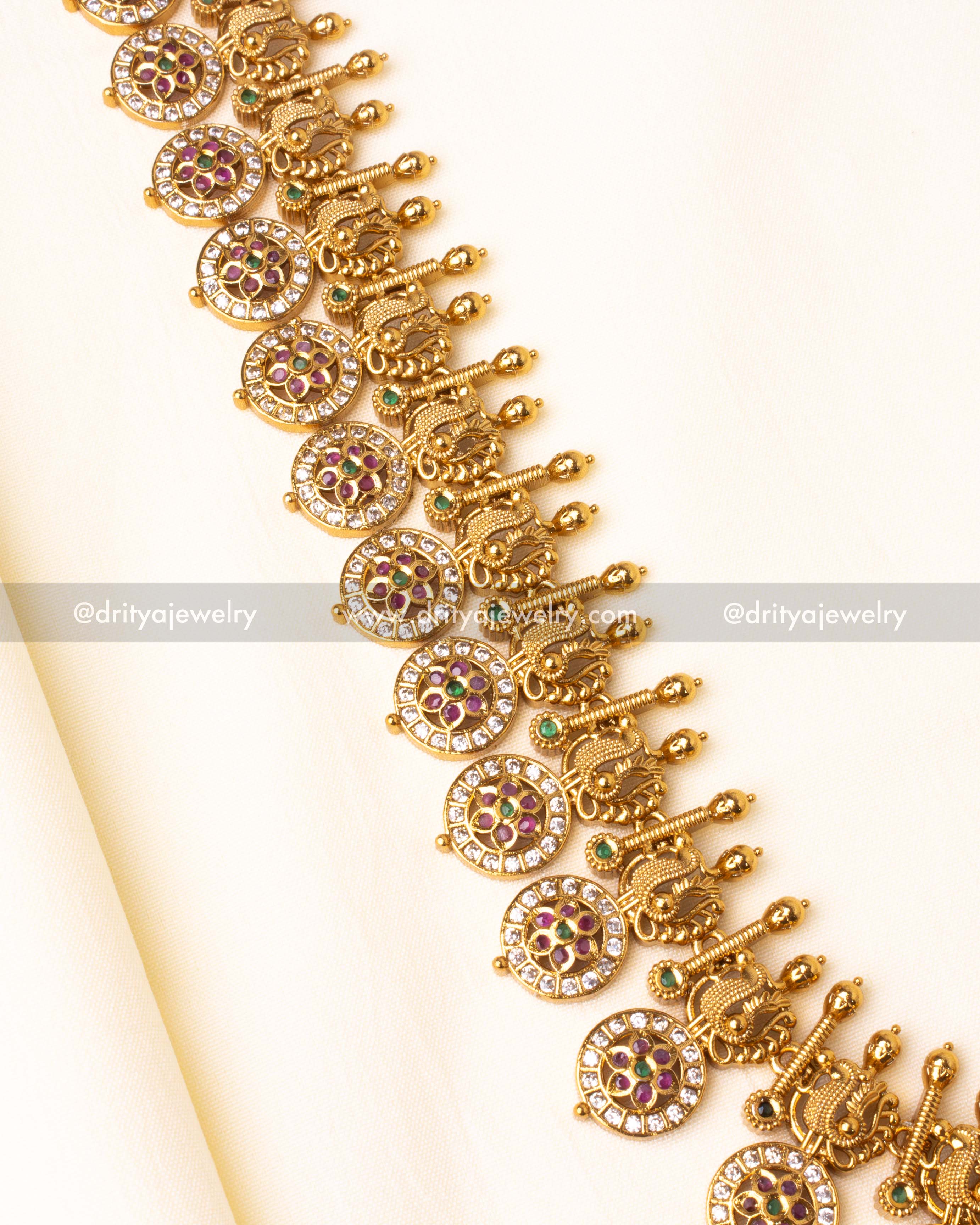 Detailed craftsmanship of gold-plated long necklace featuring traditional motifs and vibrant stone accents.