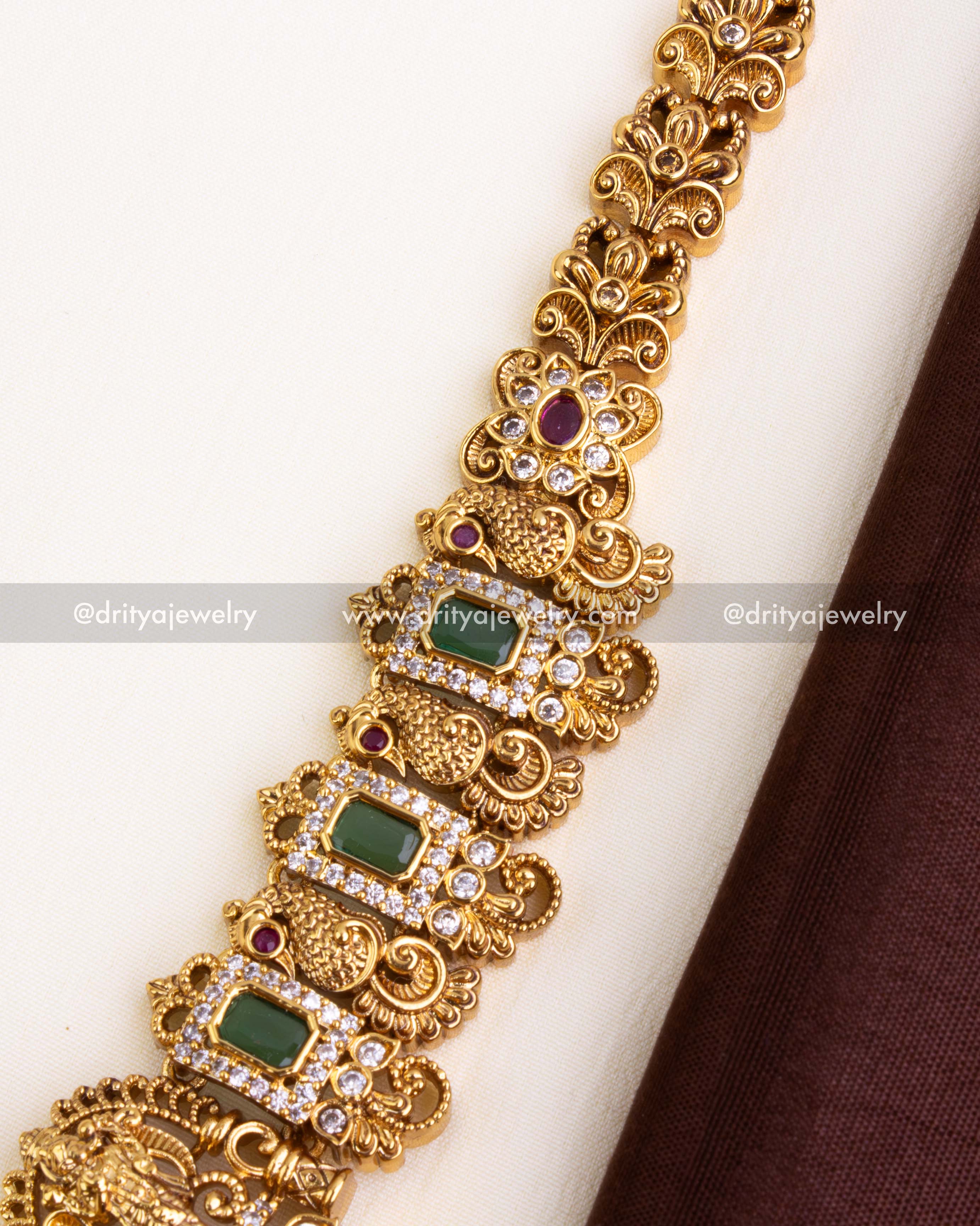 Intricate temple-style chain with green rectangular stones, ruby florals, and American Diamonds in antique finish.