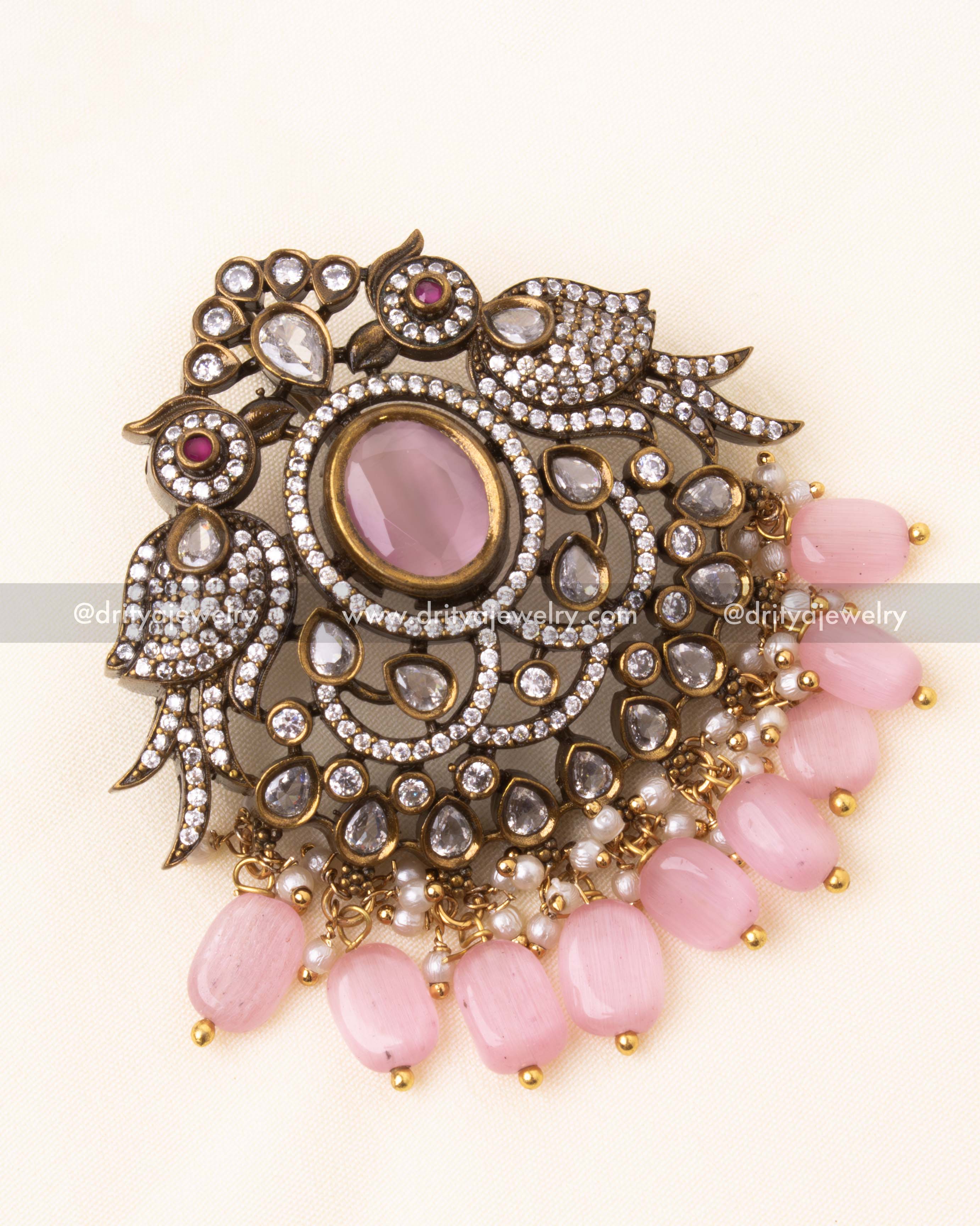 Detailed view of the Victorian pendant with bird motifs, pink center stone, and beaded drops.