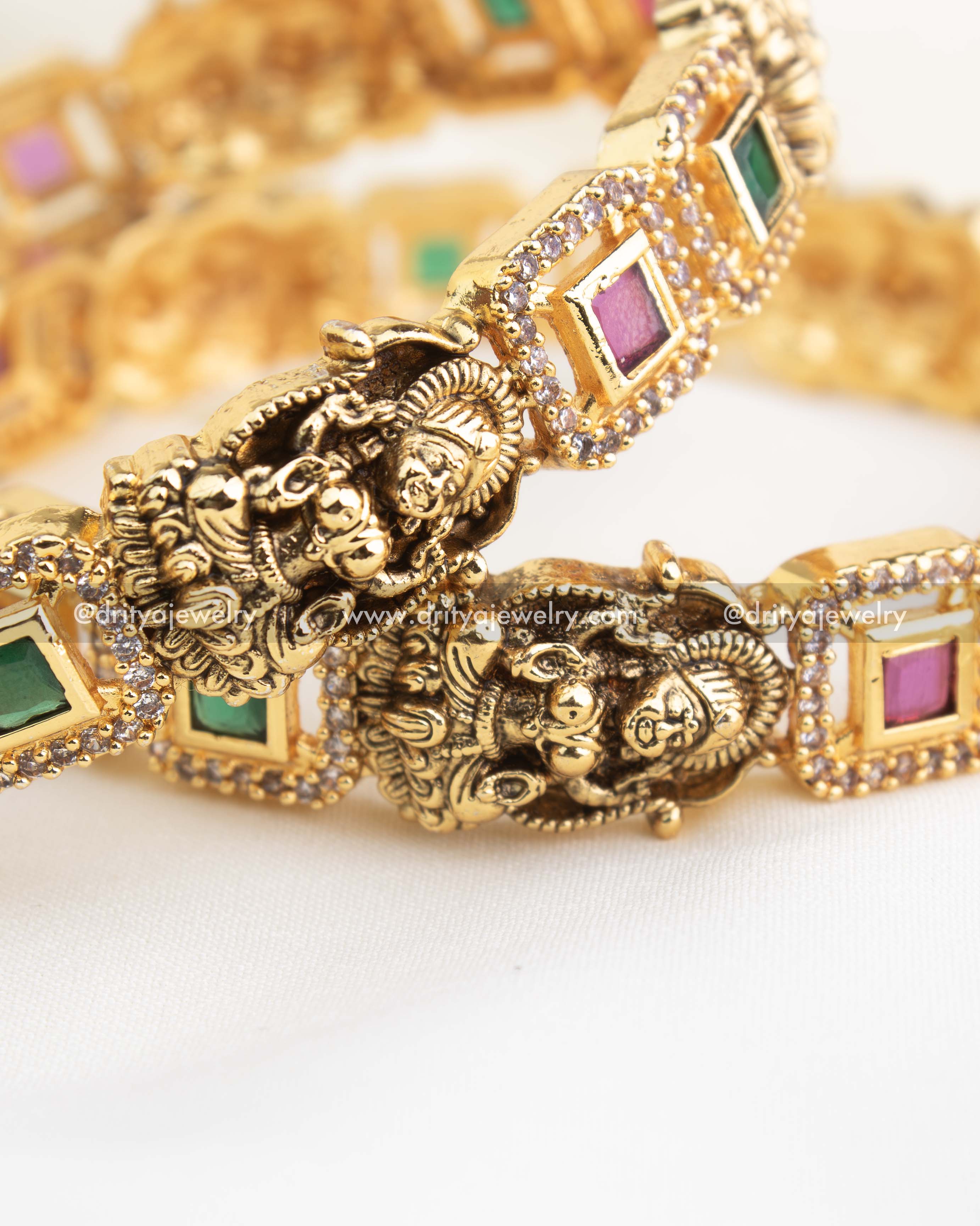 Macro view showing CZ-framed green and ruby stones with granulated temple borders.