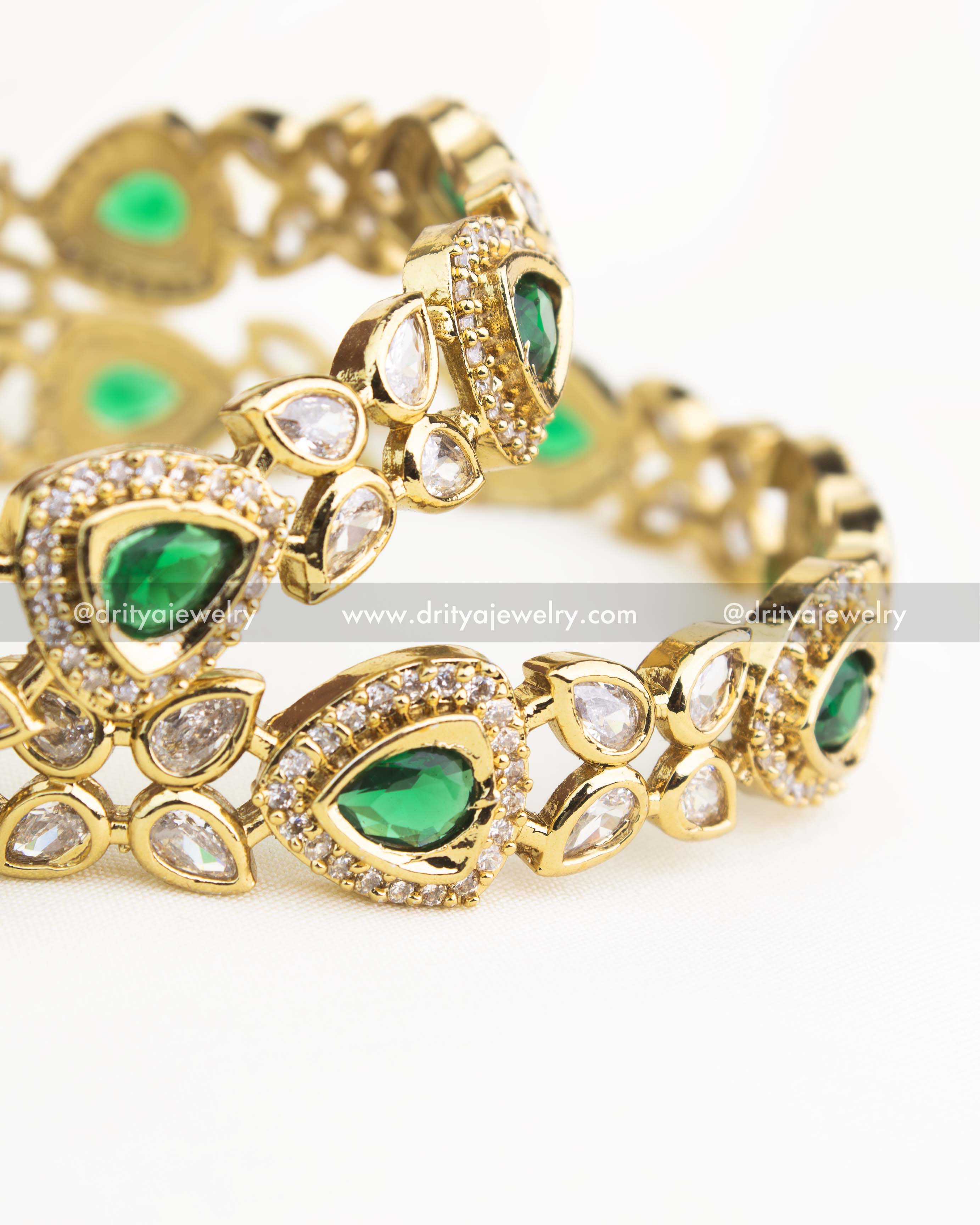 Close-up showing emerald green AD stones bordered with white zircons in Victorian gold finish.