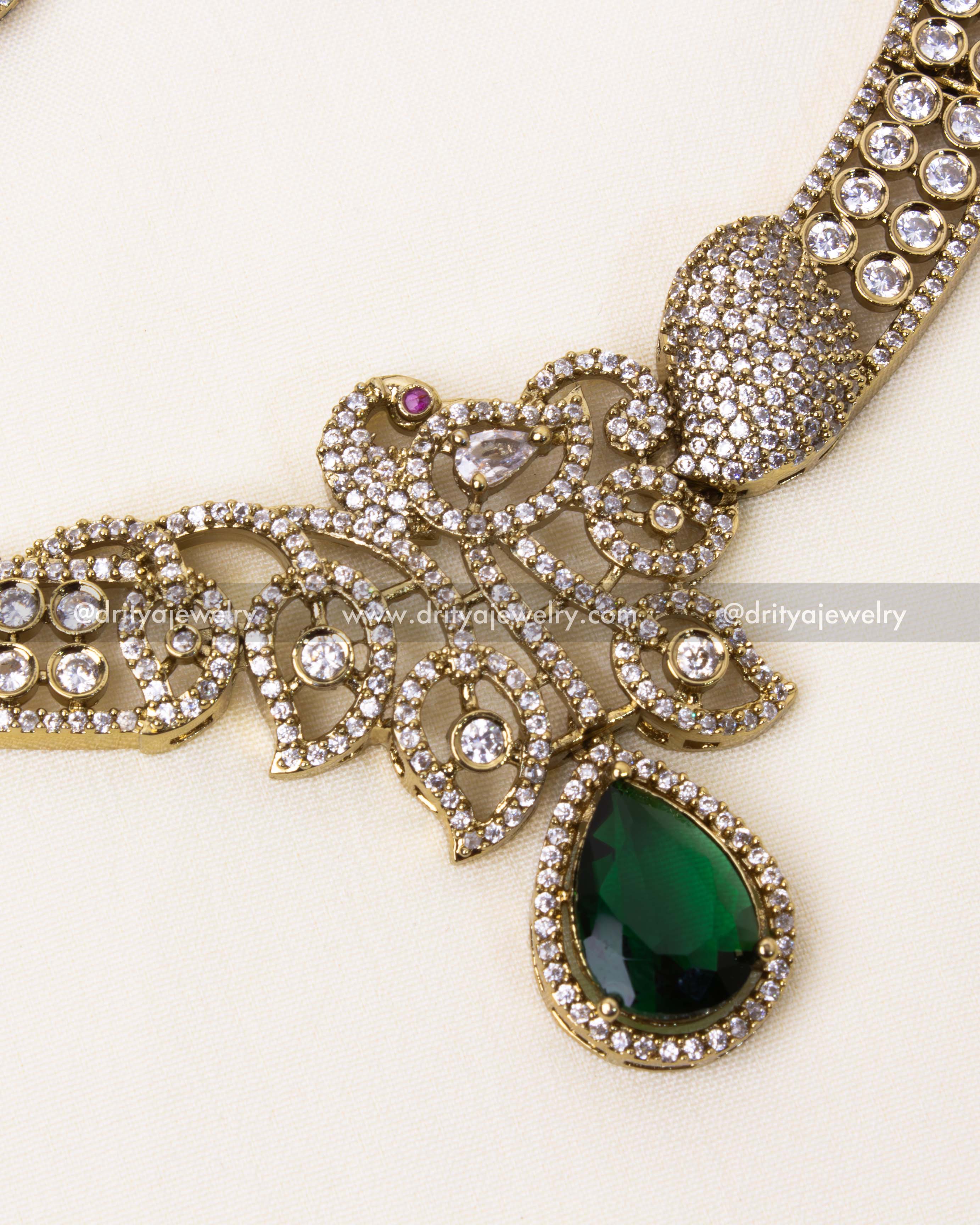 Intricate peacock motif with a teardrop emerald gemstone and Victorian-style detailing.